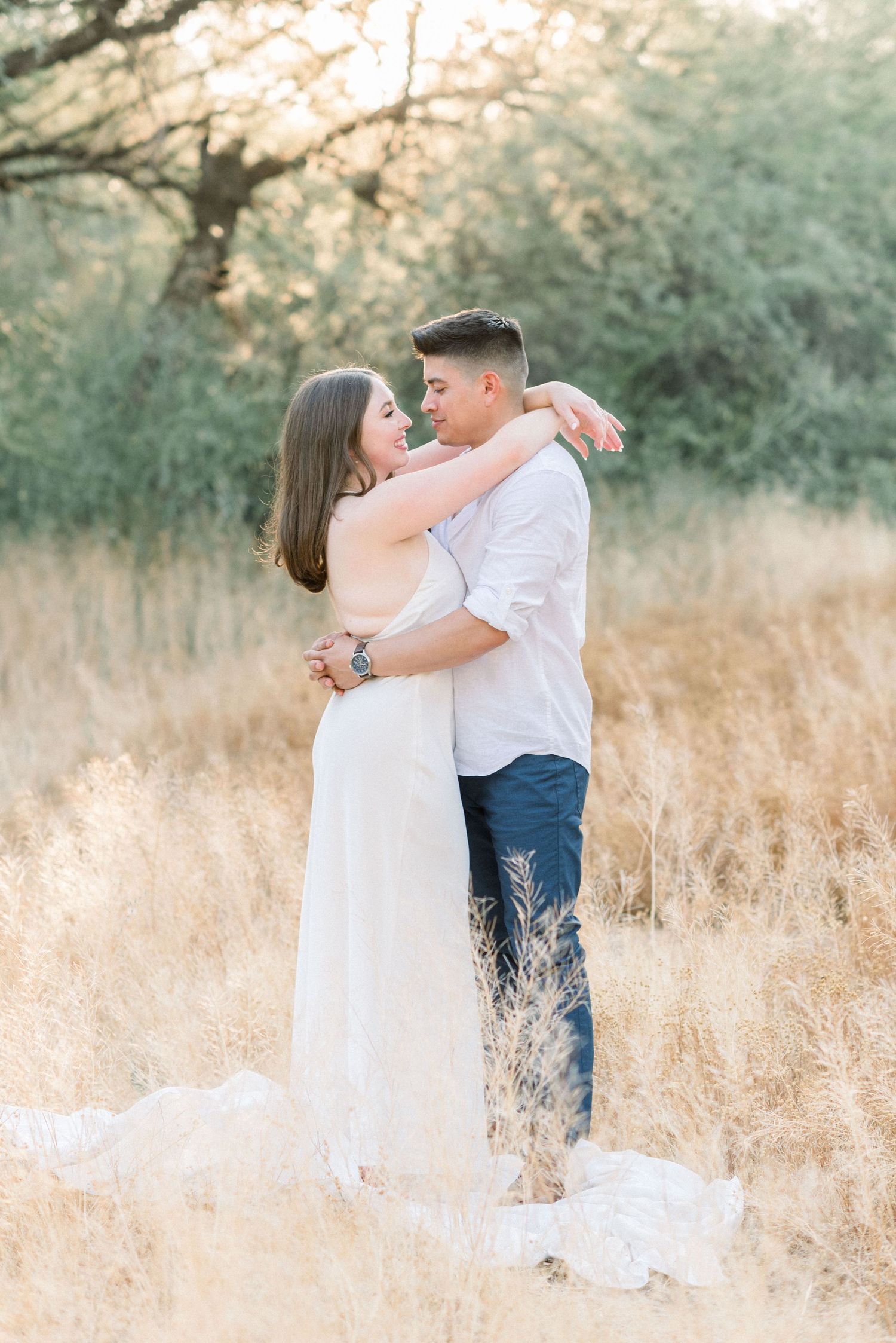 A tender embrace between a couple standing in a field of tall golden grass.