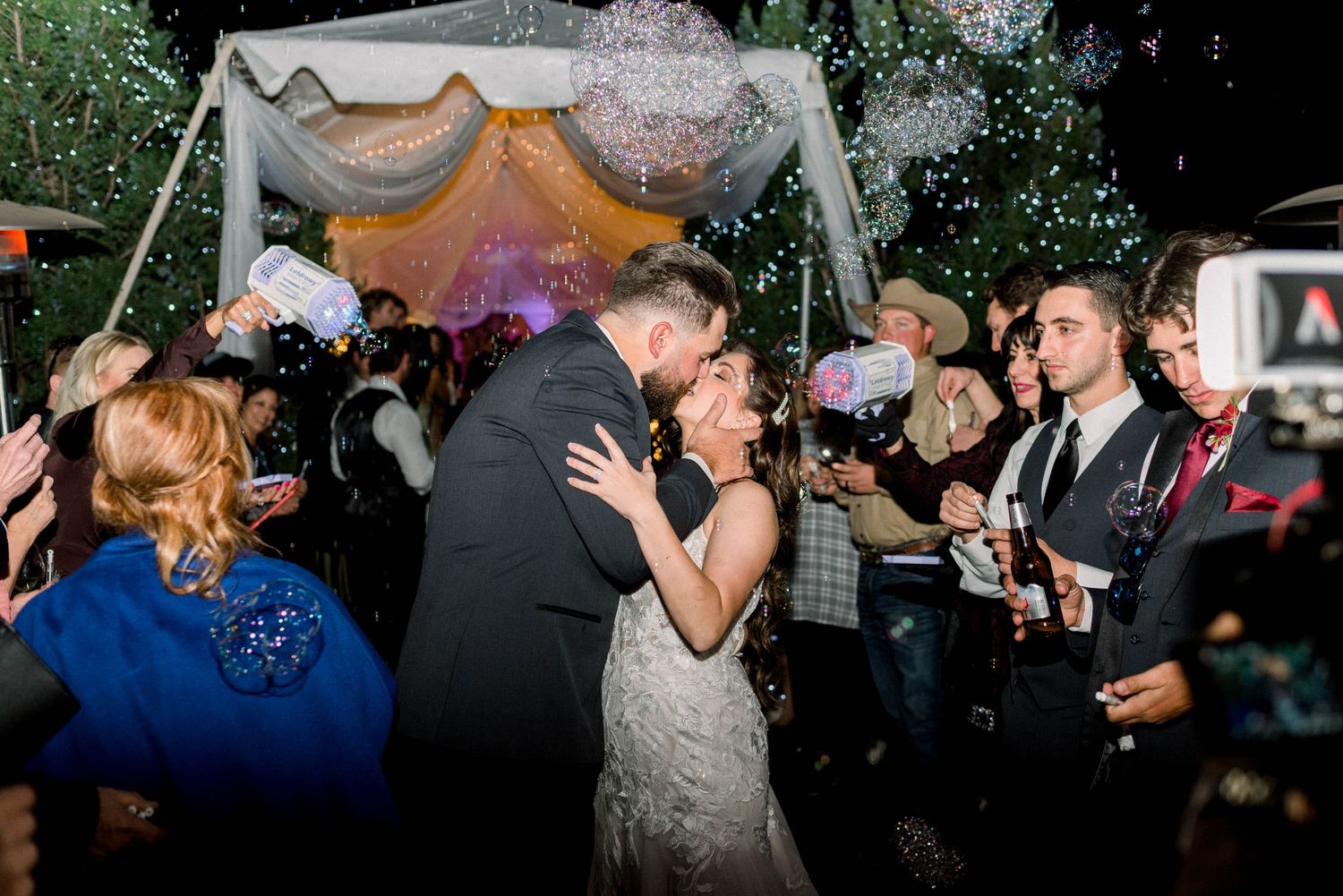 Romantic celebration moment under tent with confetti and guests at evening wedding reception.