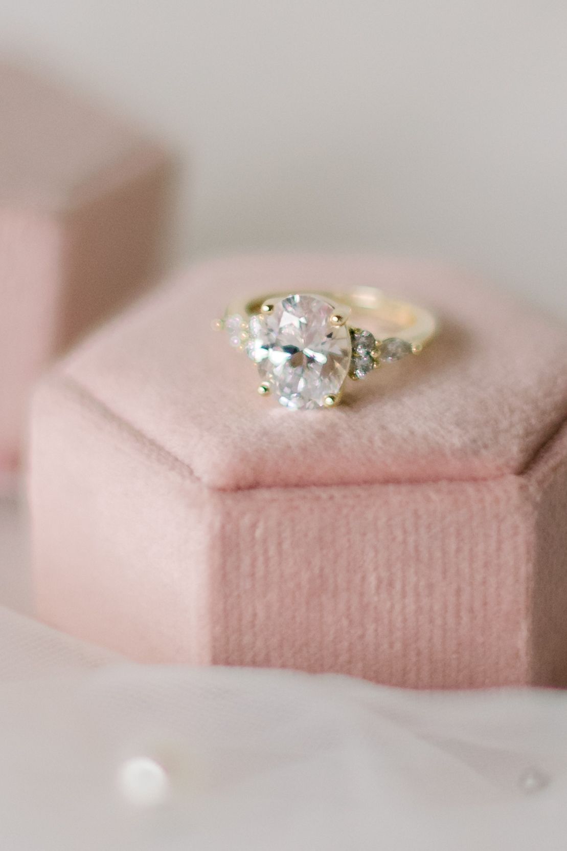 Elegant diamond engagement ring displayed on a soft pink velvet hexagonal ring box.