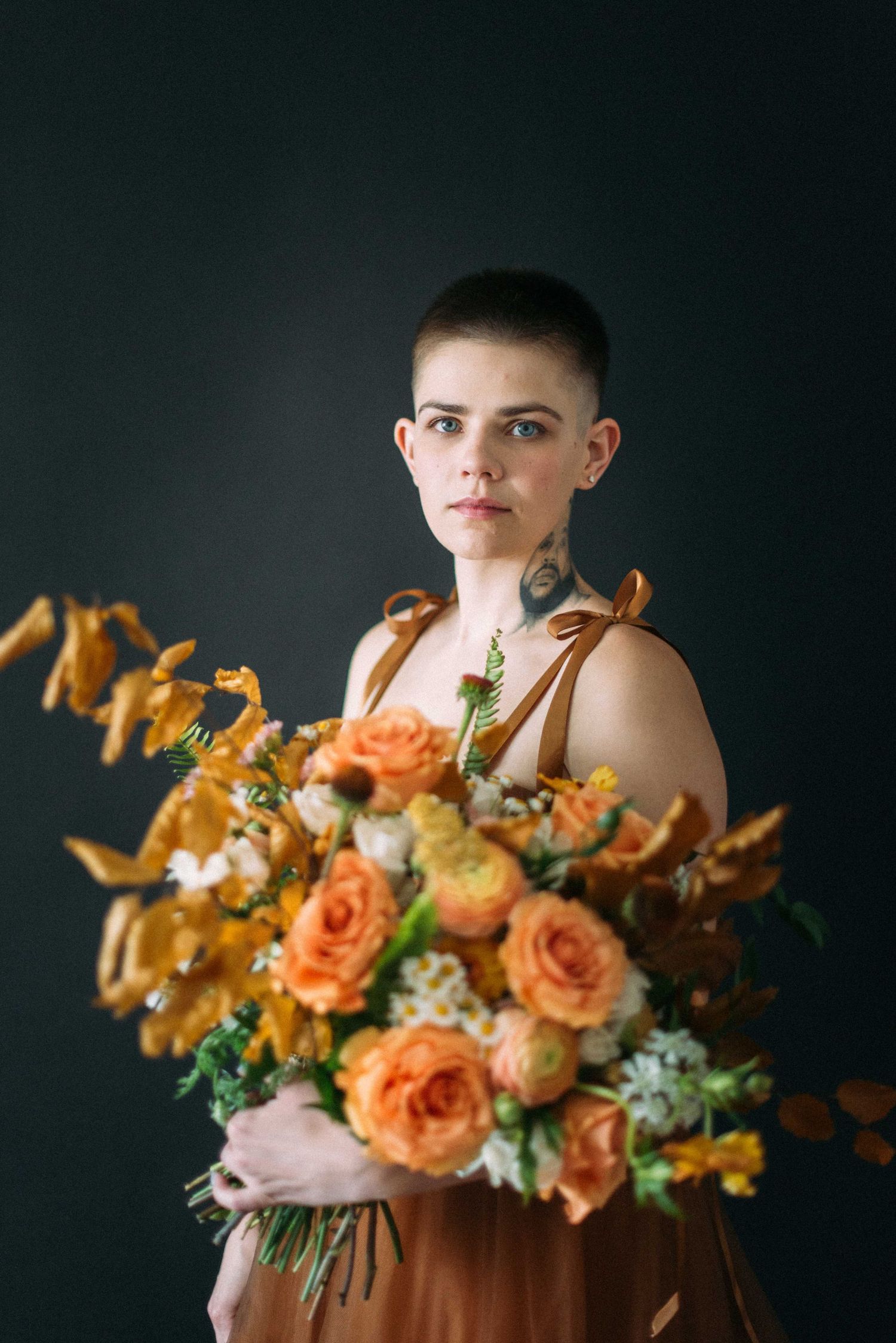 An artistic portrait with autumn-colored florals against a dark background.
