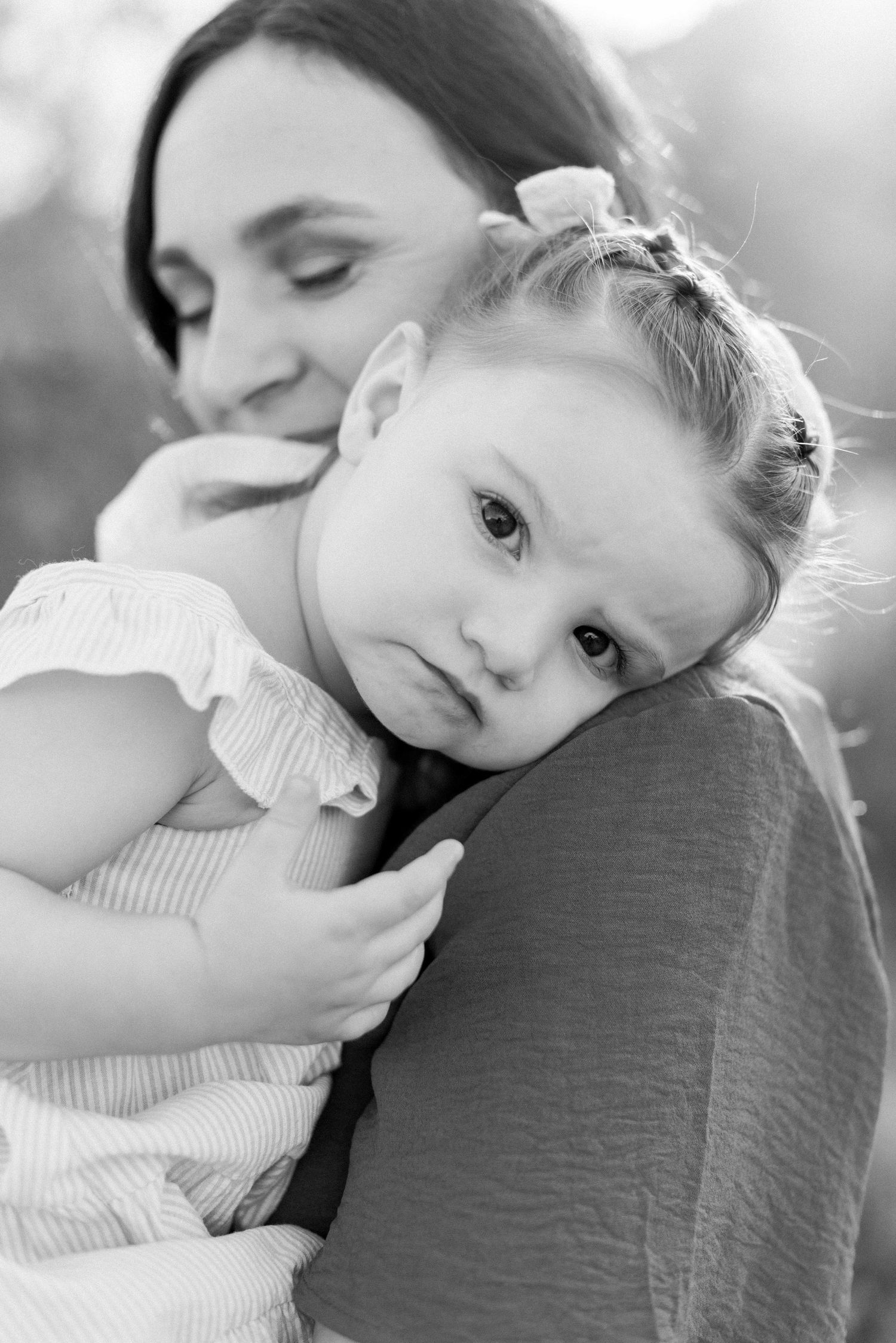 Sweet tender moment captured in black and white as child rests on shoulder.