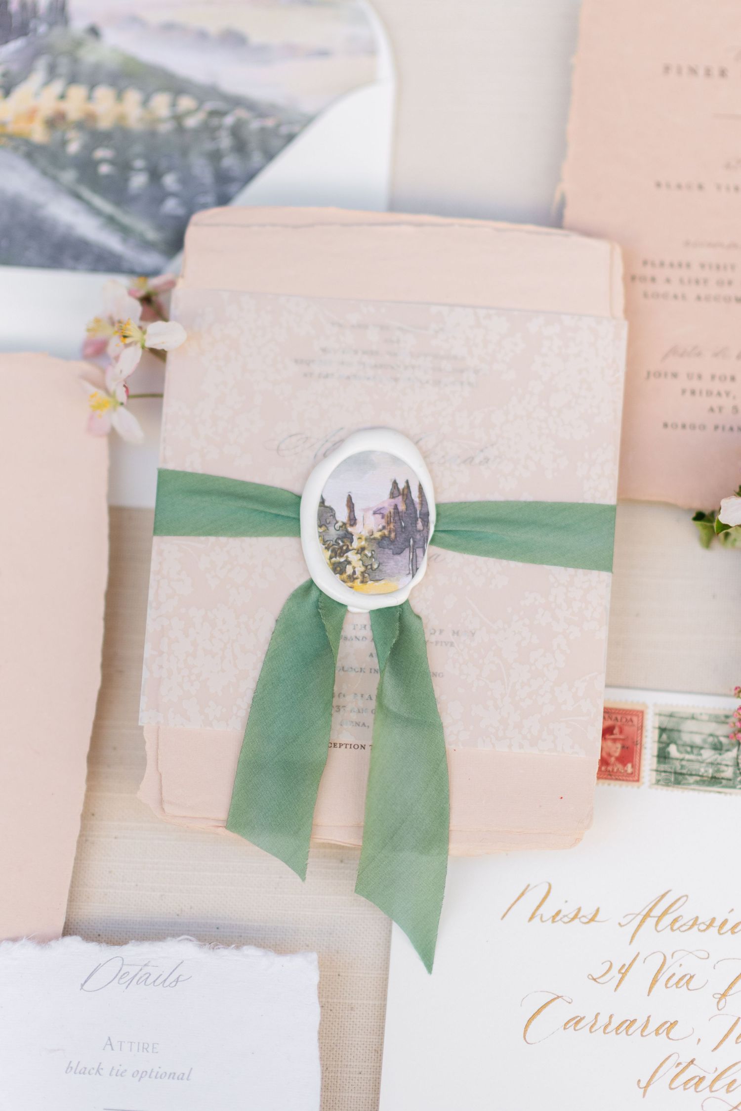 Elegant wedding invitations with green ribbon and wax seal details.