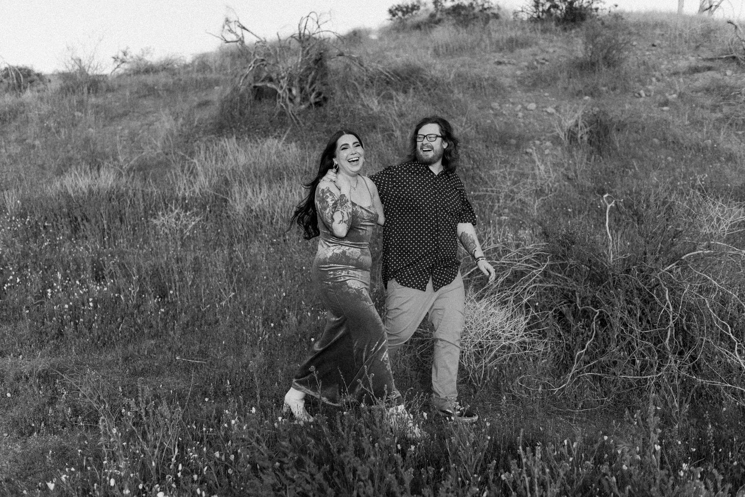 A group of people walking through a grassy field in black and white vintage photograph.