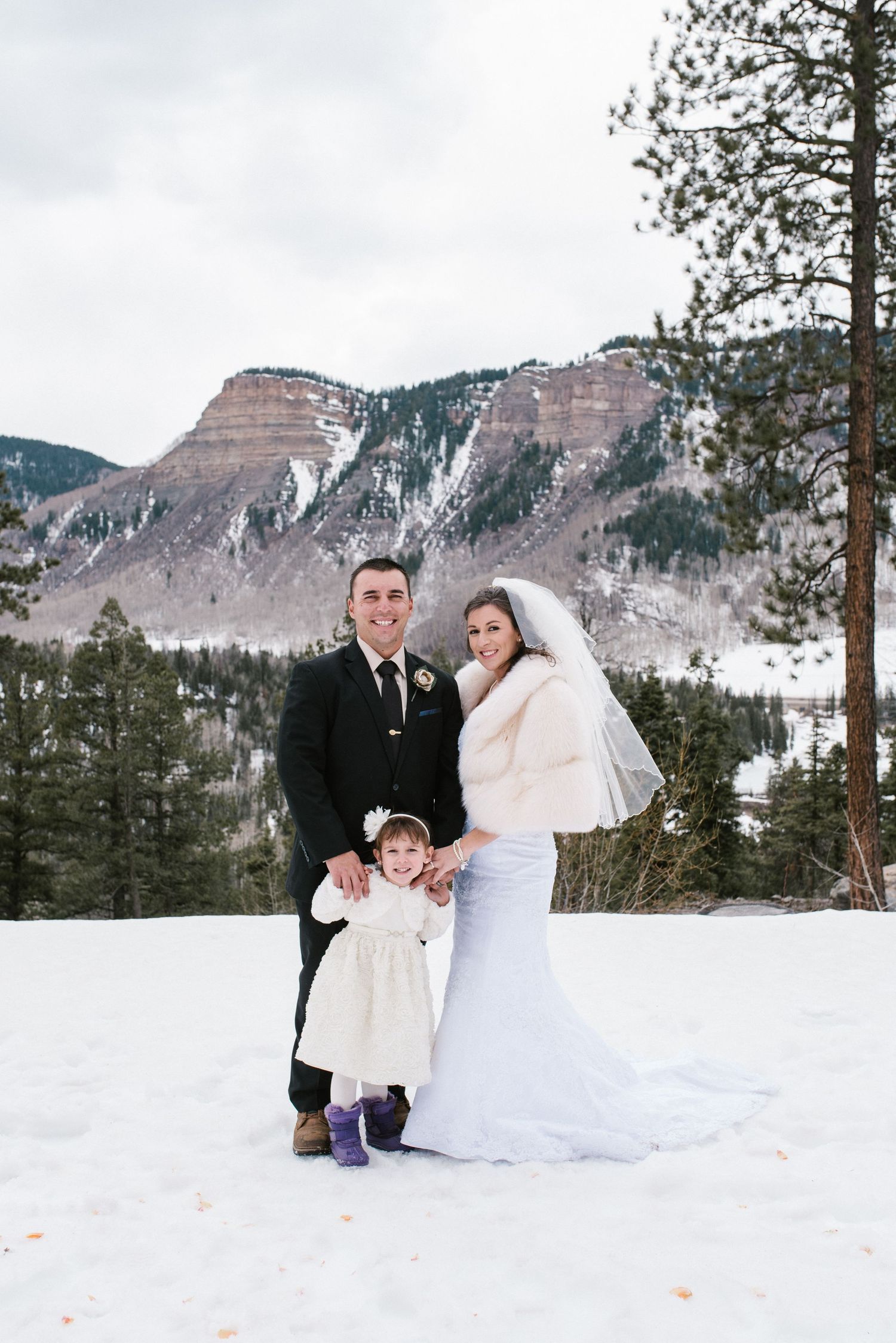 Winter wedding portrait with snow-capped mountains in the background.