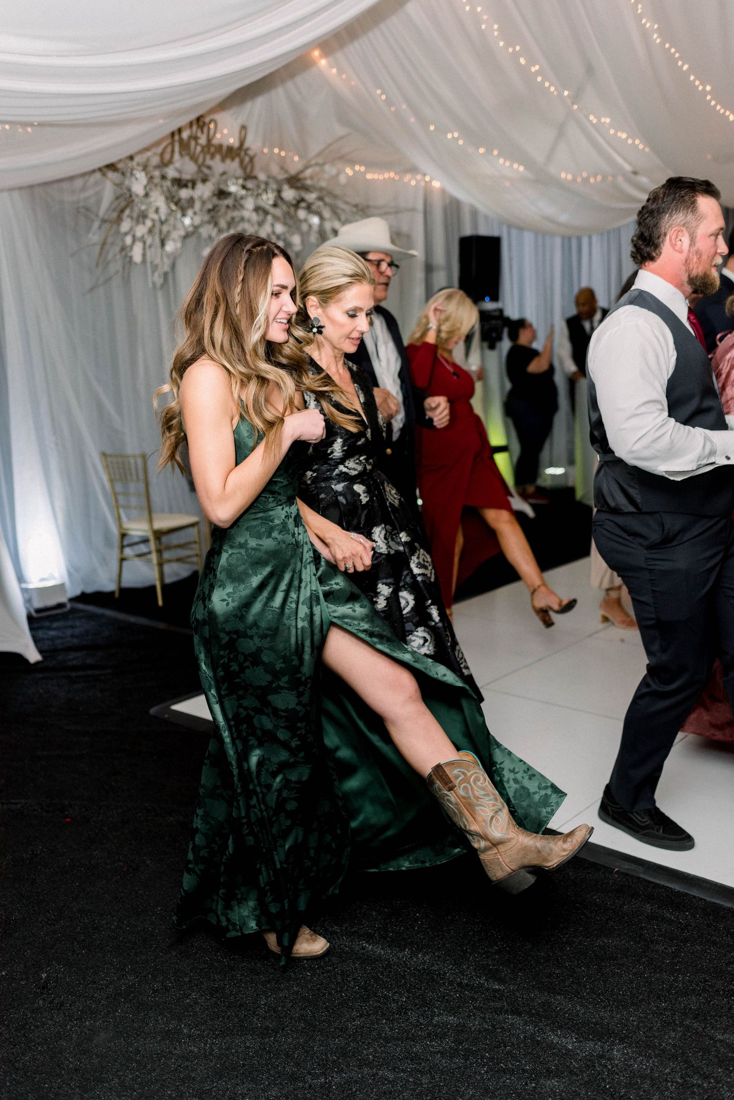 Wedding guests dancing and celebrating in formal attire at an indoor reception.