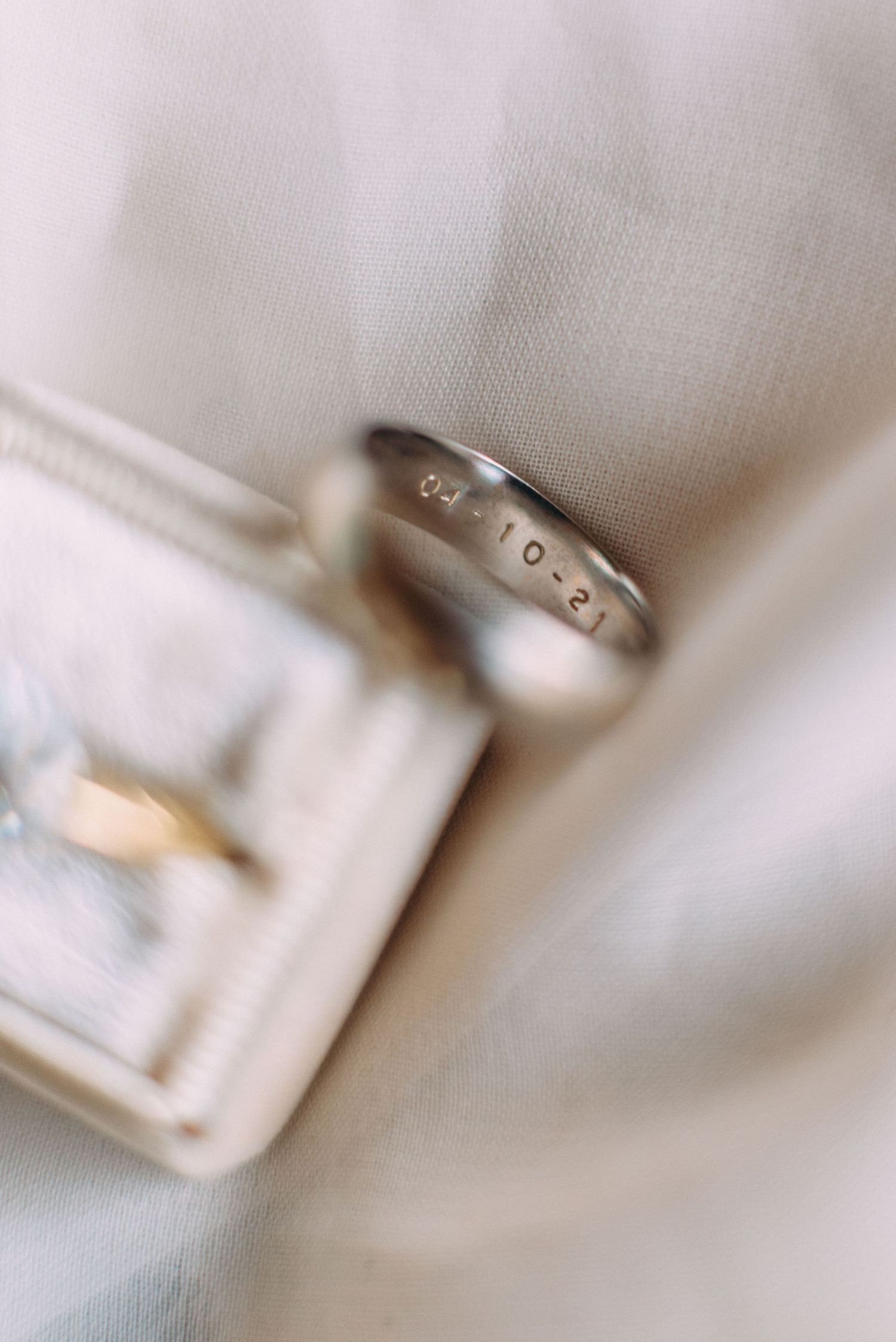 Wedding band with engraved text resting against a white ring box.
