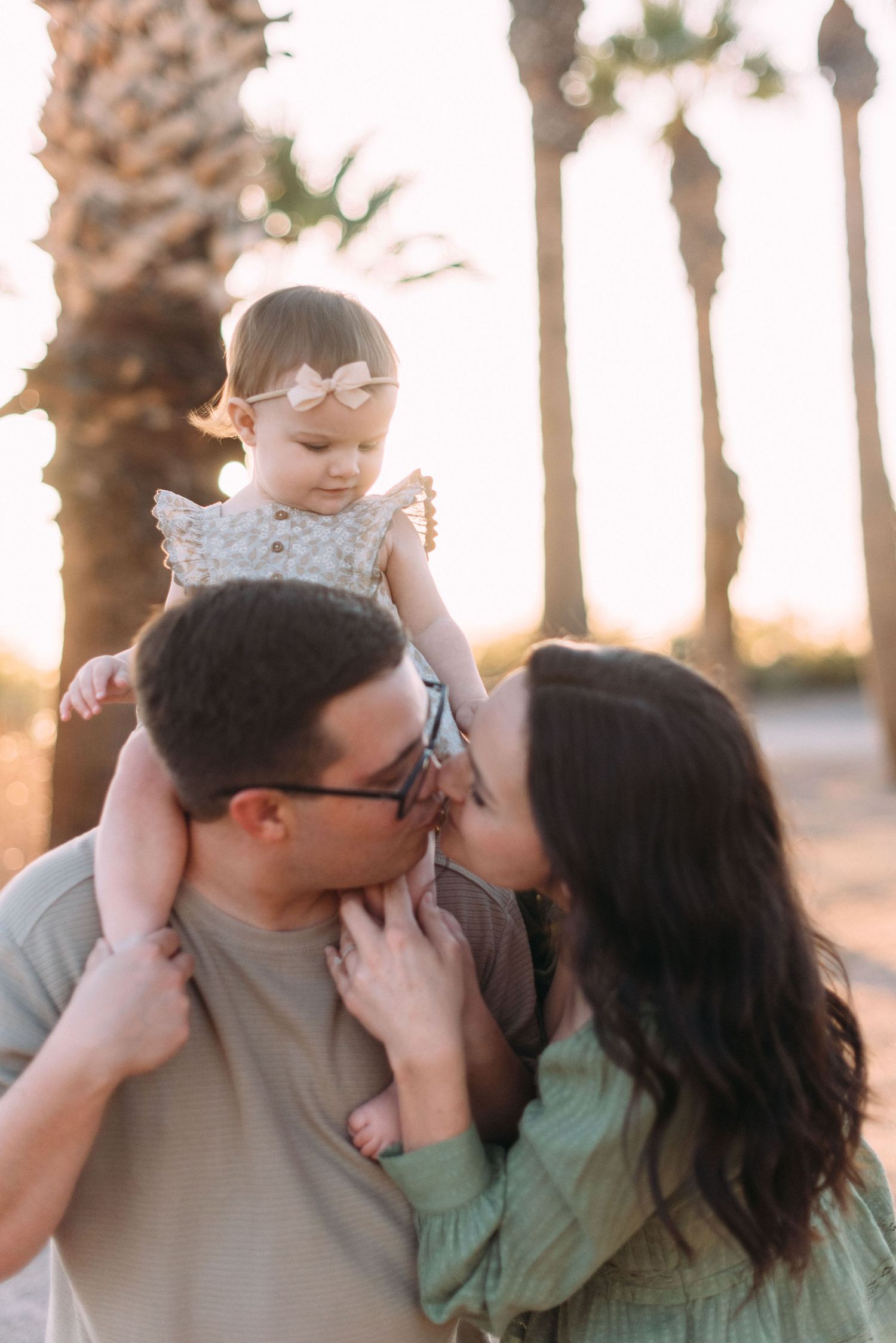 Candid family moment captured at sunset with palm trees in background.