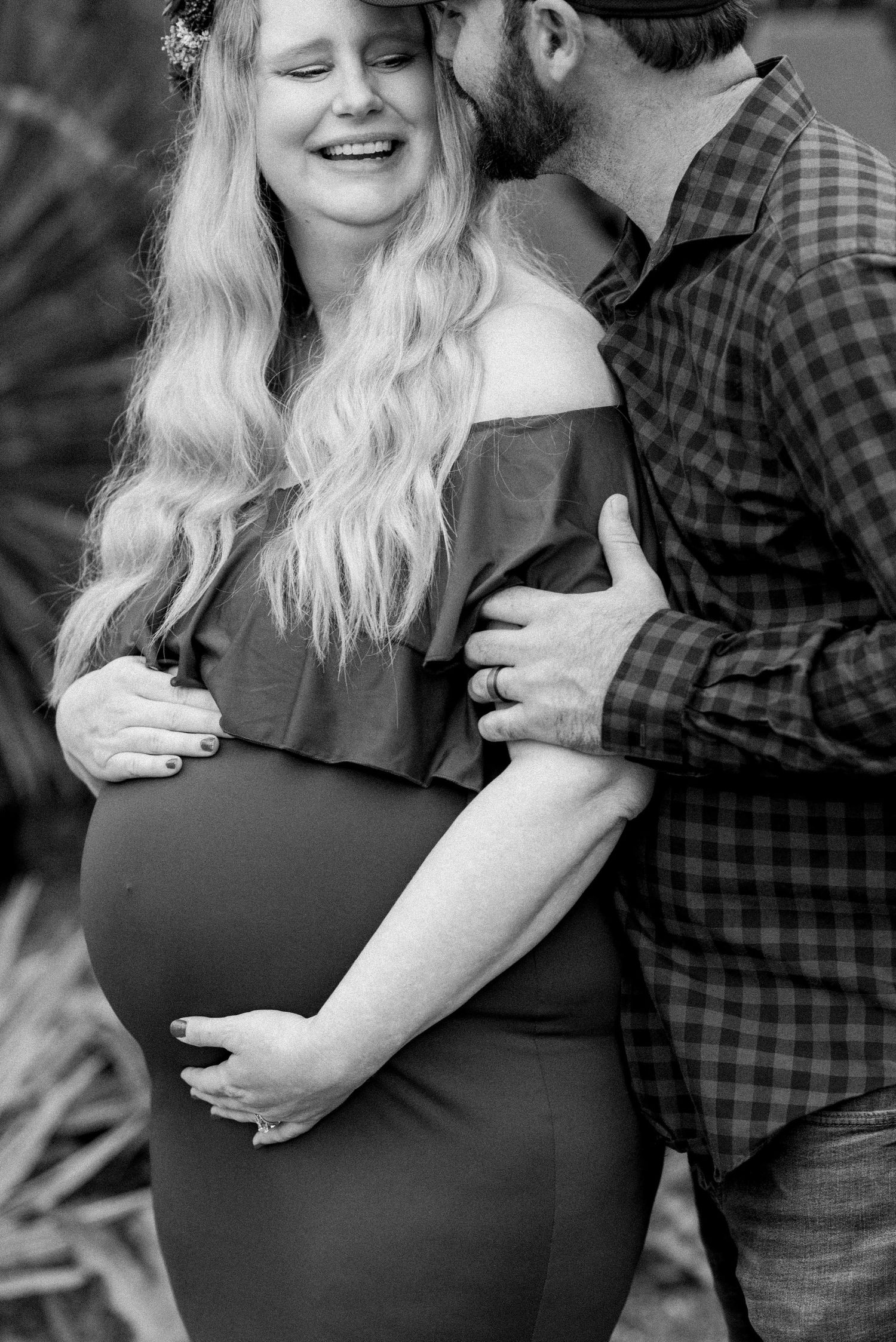 Black and white intimate maternity moment captured in casual outdoor setting.