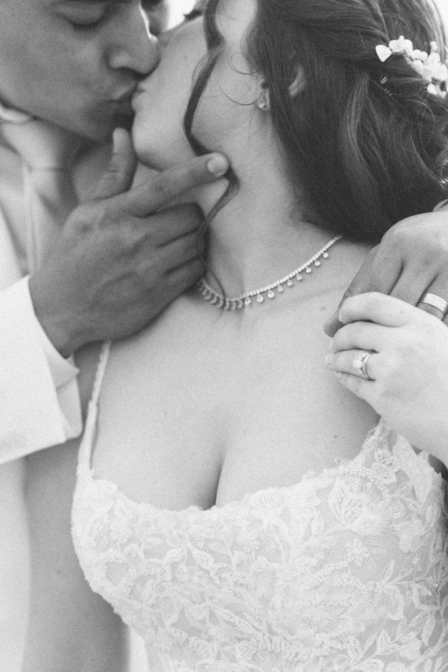 A close-up black and white wedding photo showcasing intricate lace details and a pearl necklace.