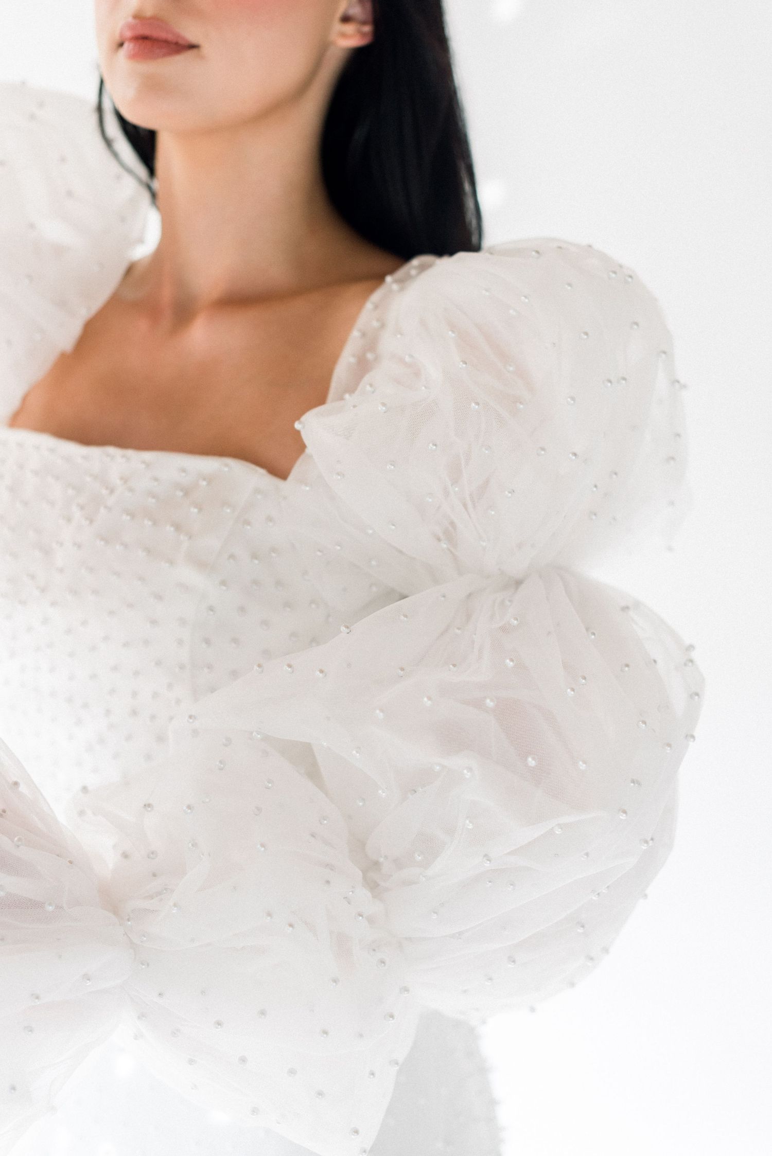 Close-up of white wedding dress featuring detailed puffy sleeves and textured fabric.