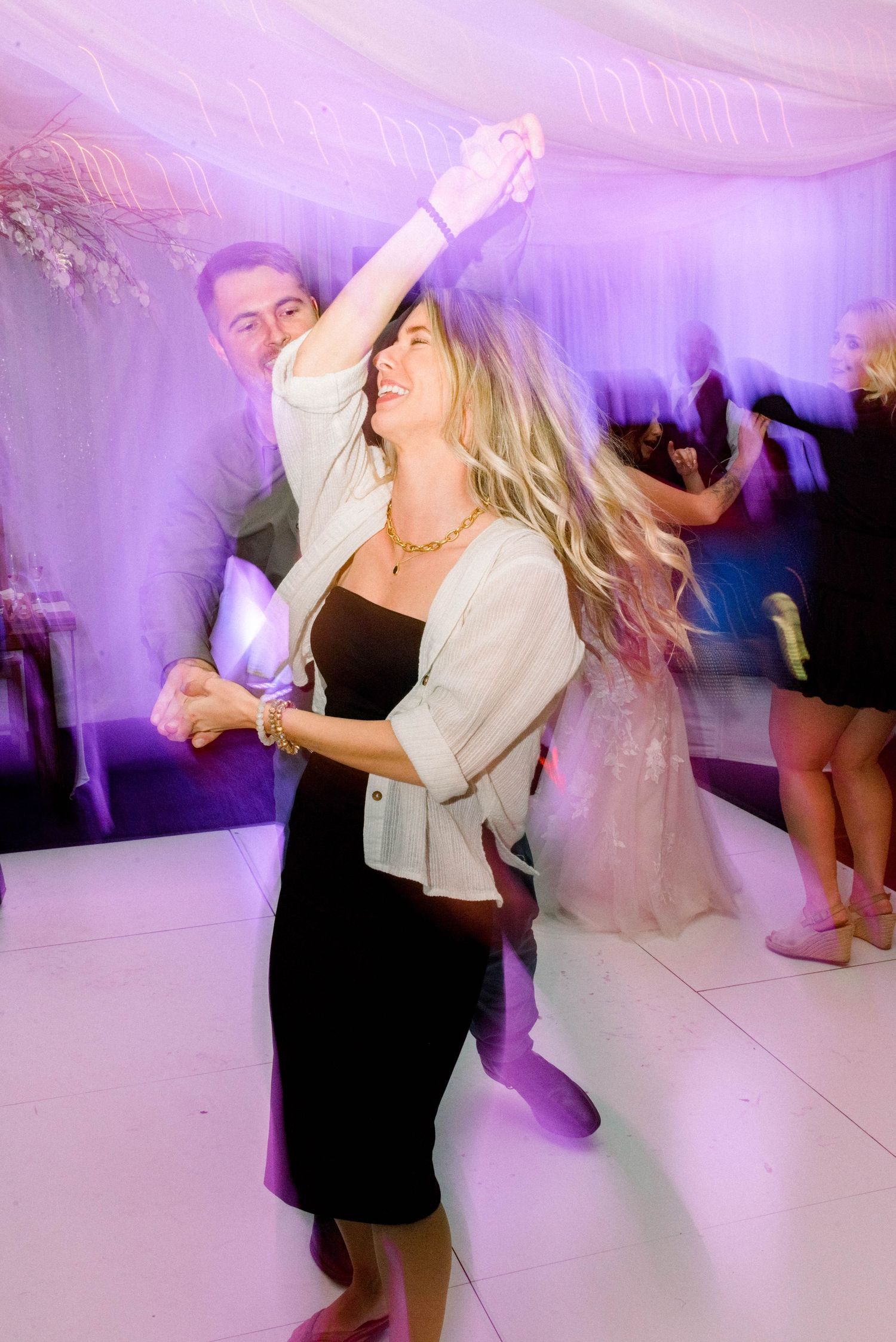 Wedding guest dancing energetically on illuminated dance floor during reception party.