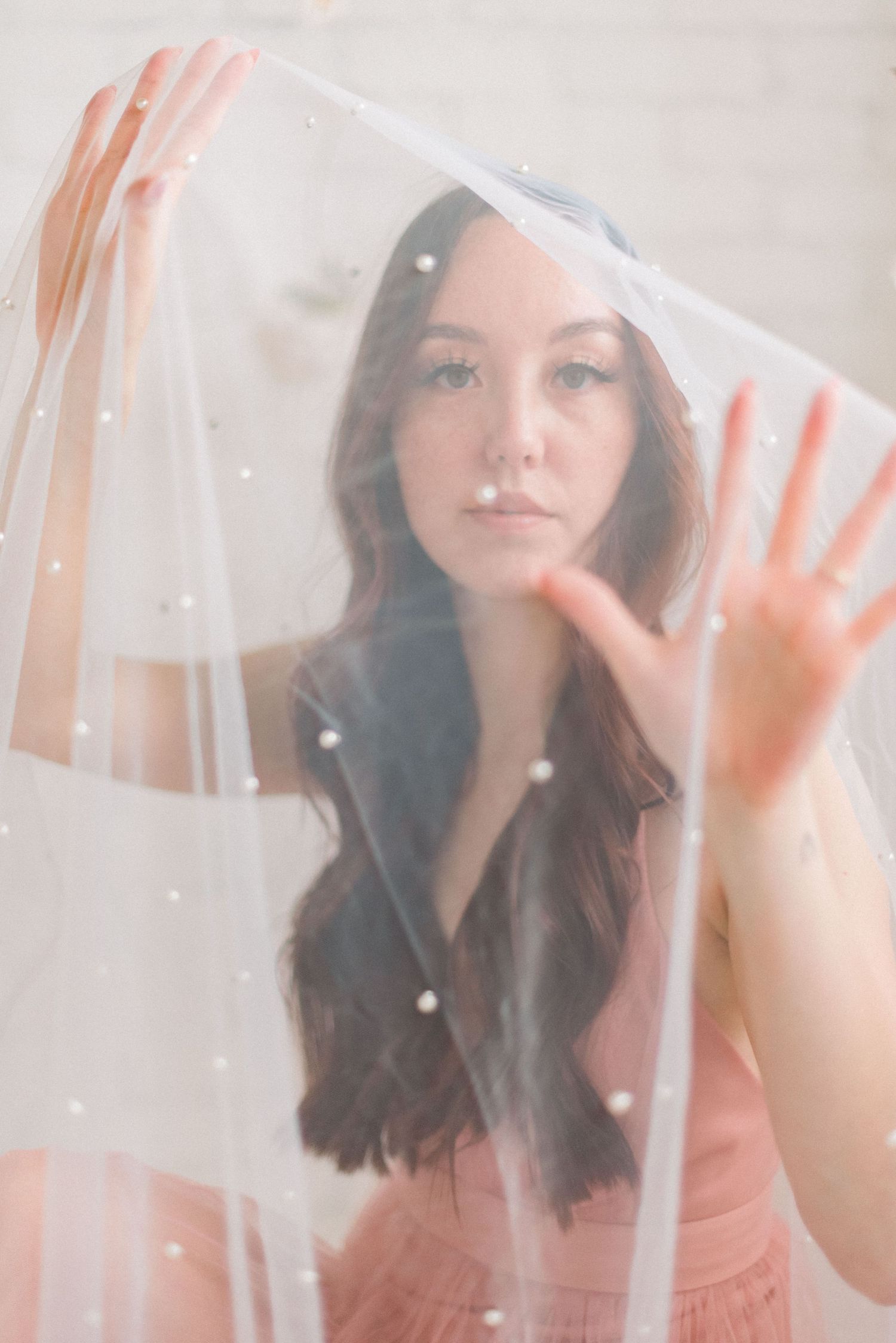 Romantic portrait through transparent veil with gentle pastel tones.