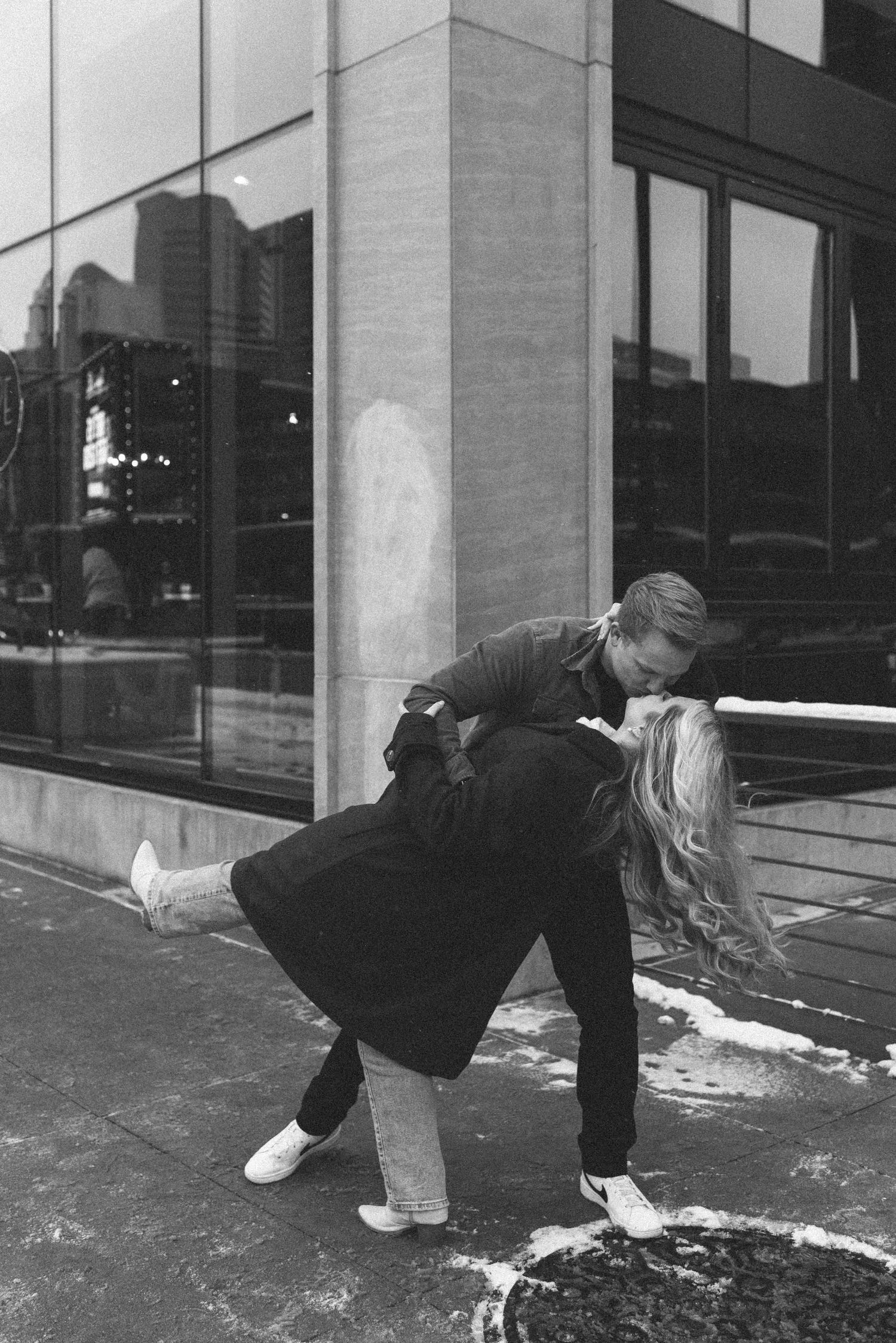 Romantic black and white dance dip pose outside modern building.