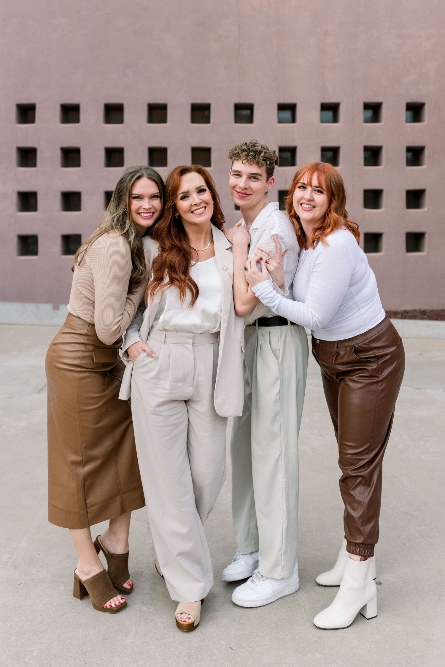 Group photo in coordinated earth-tone outfits against modern architectural backdrop.