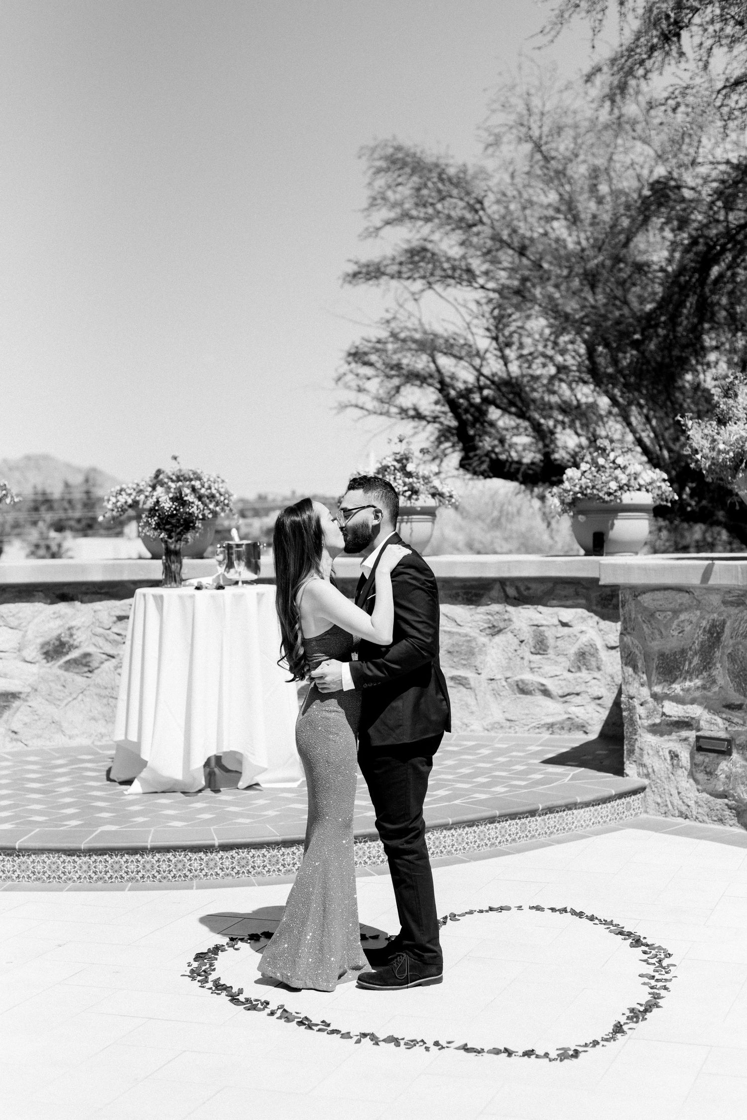 Black and white photo of a couple's romantic moment inside a heart shape of petals.