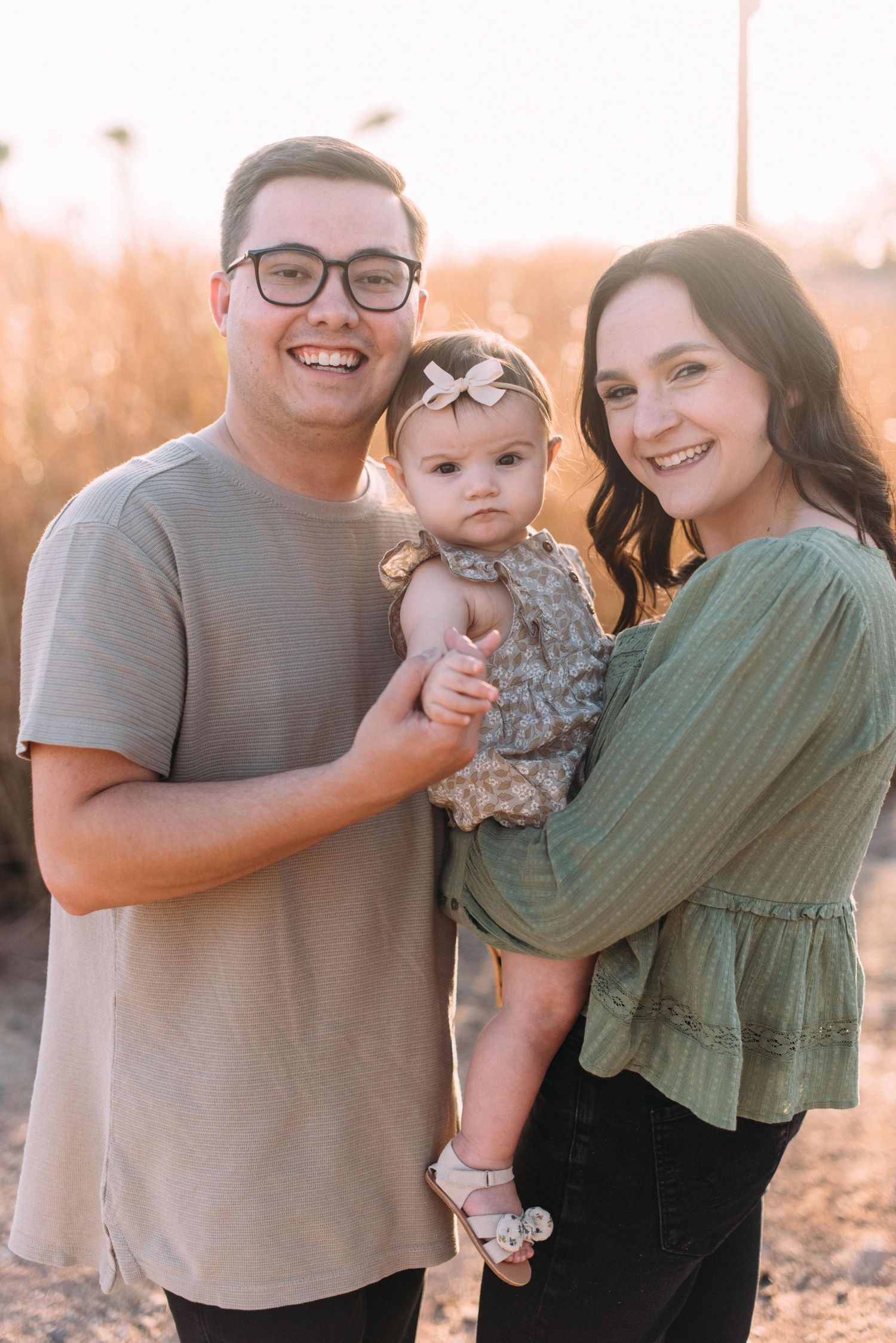 Family portrait at sunset with baby in floral dress.