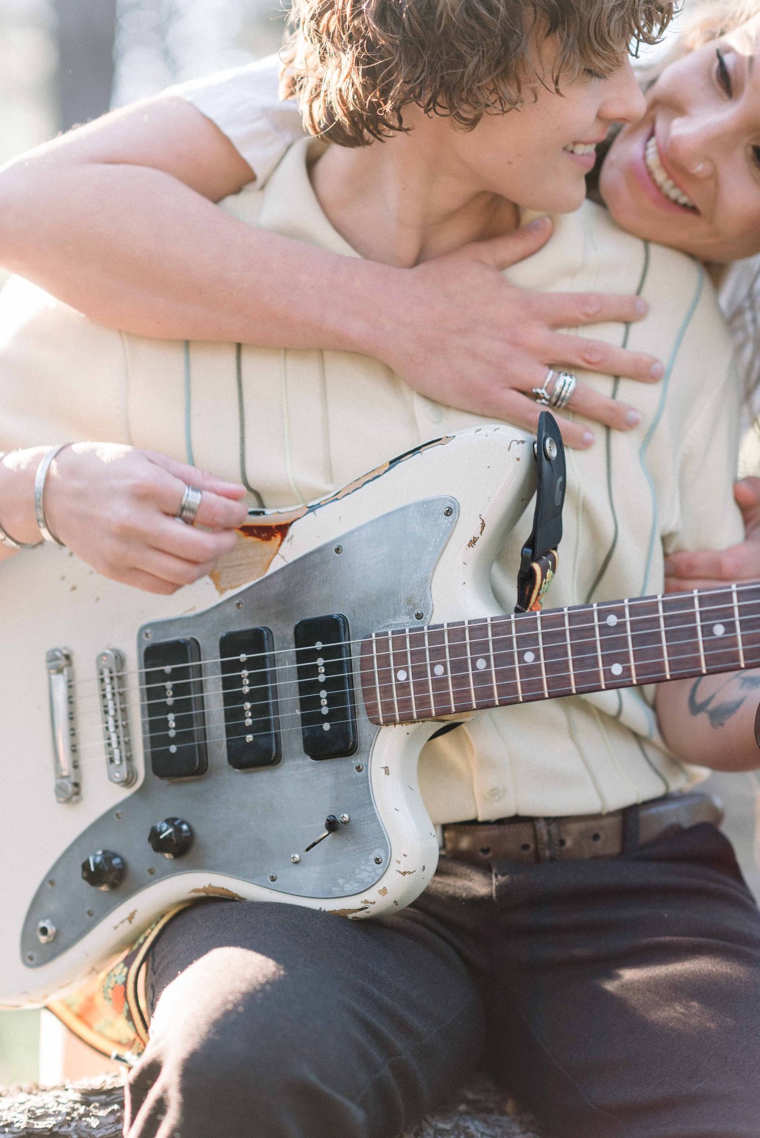 A tender moment shared between couple with a white electric guitar outdoors.