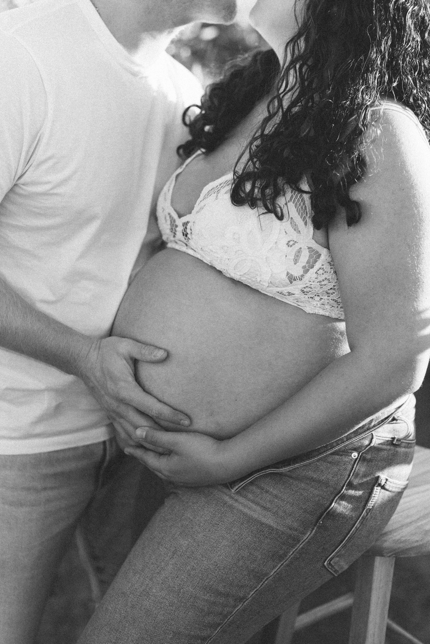 Black and white maternity photo of couple kissing in sunflower field