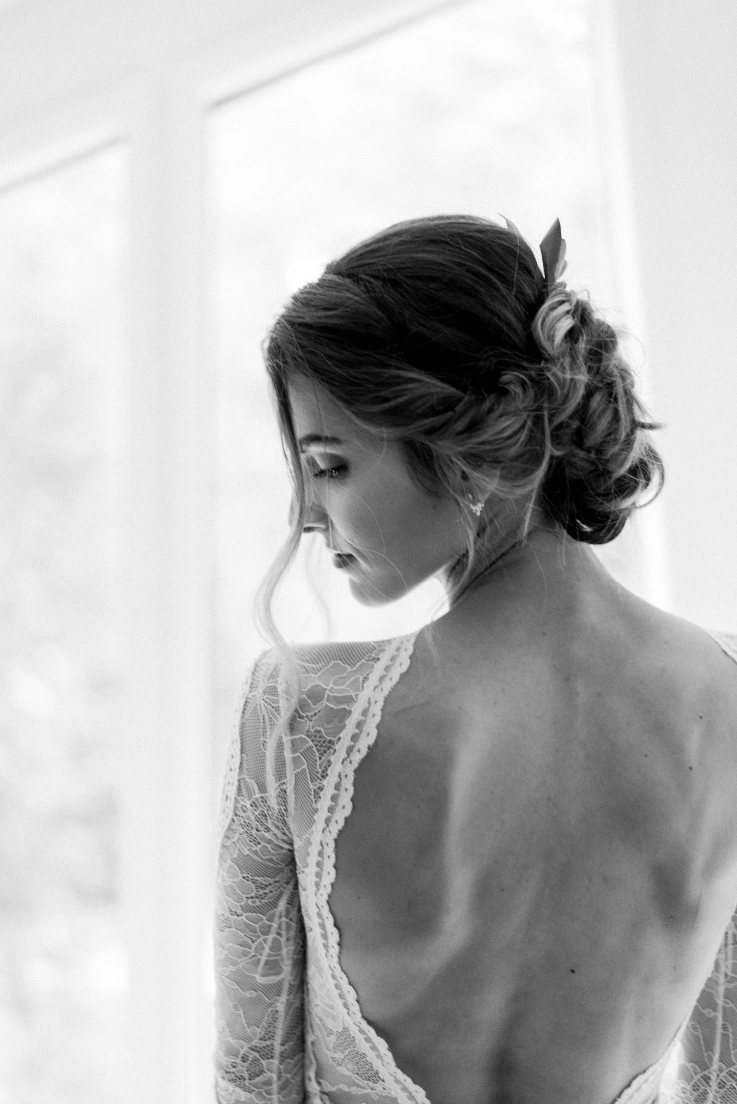Black and white portrait showing intricate lace details of a backless wedding dress.
