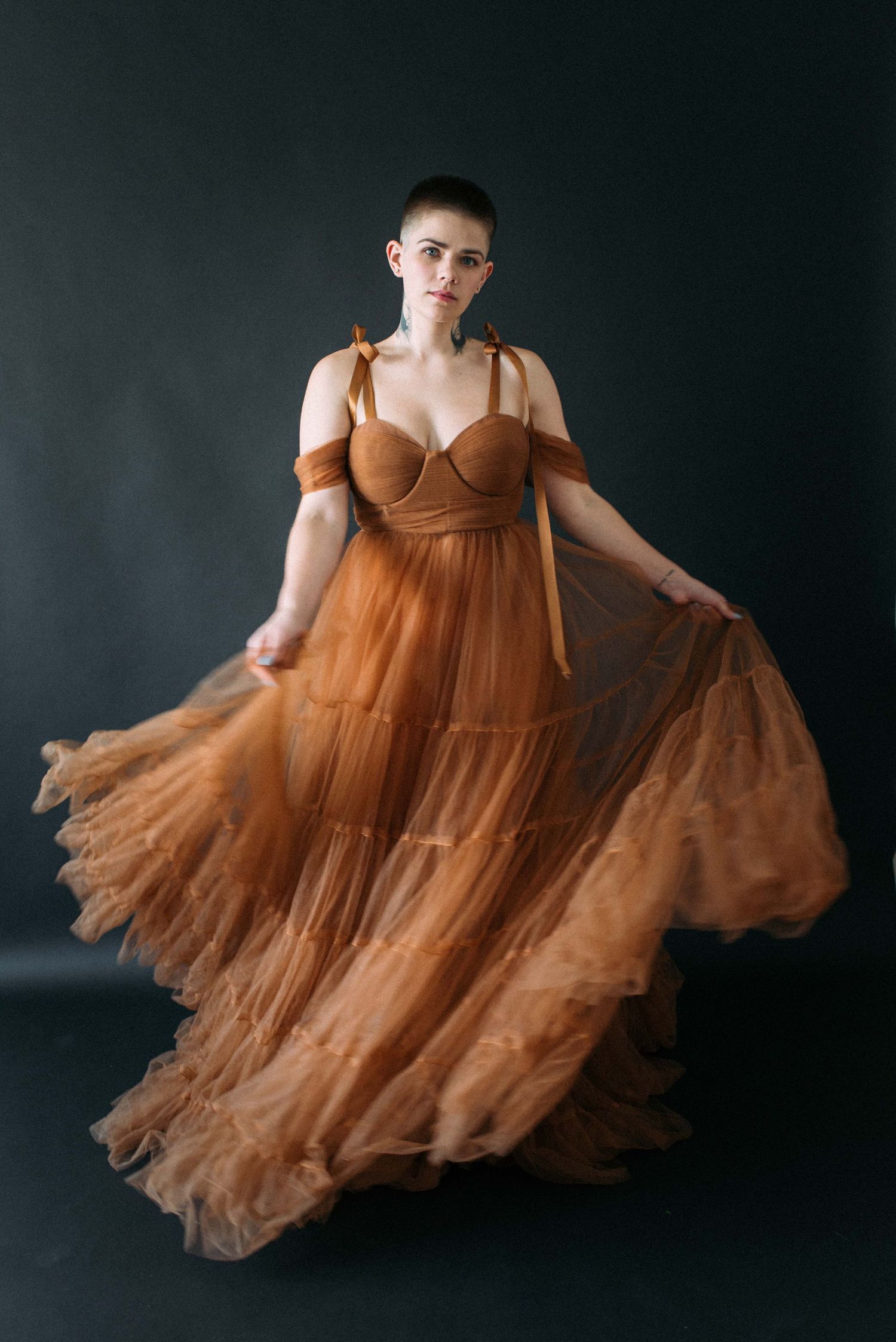 A flowing brown tulle gown creates movement in this dramatic studio portrait.