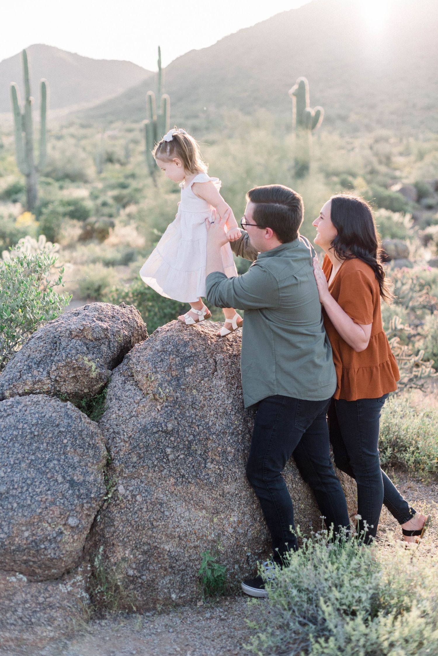 Family enjoys sunset moment together among desert cacti and rock formations.