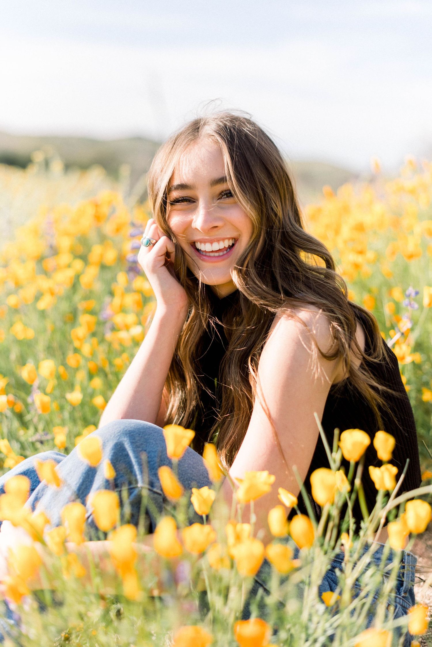 Joyful portrait surrounded by bright yellow poppies in a sunny meadow.