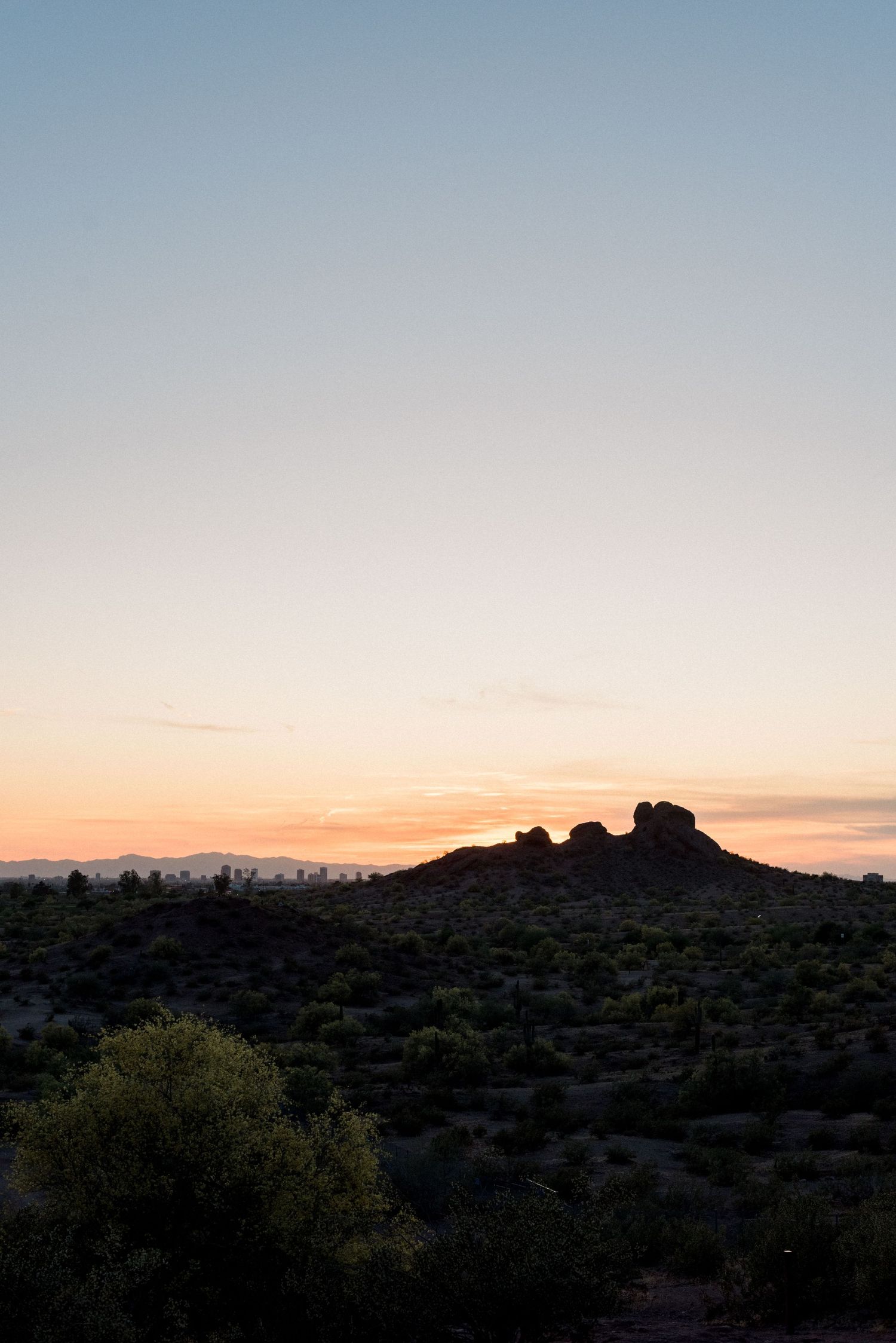 Desert landscape silhouette at sunset with mountain ridge and clear sky.