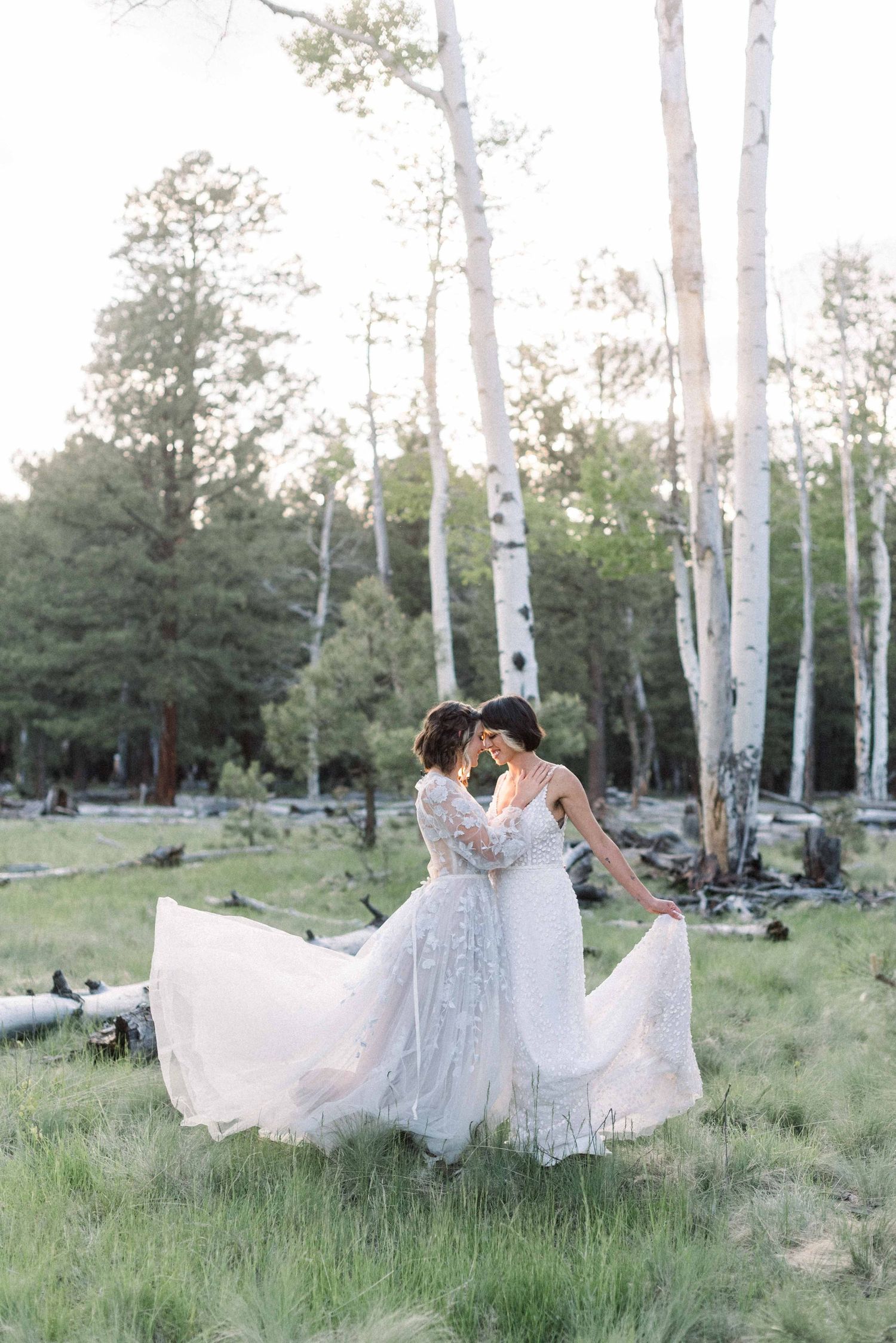Wedding couple dancing in a meadow with aspen trees and evergreens in the background.