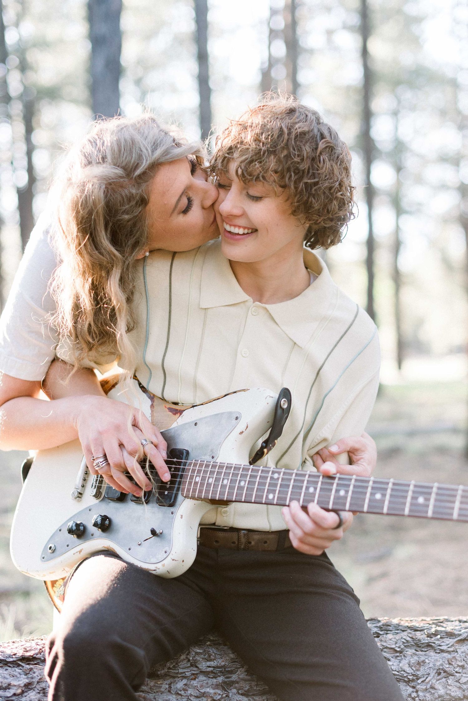 Sweet moment between couple playing electric guitar together in a forest setting.