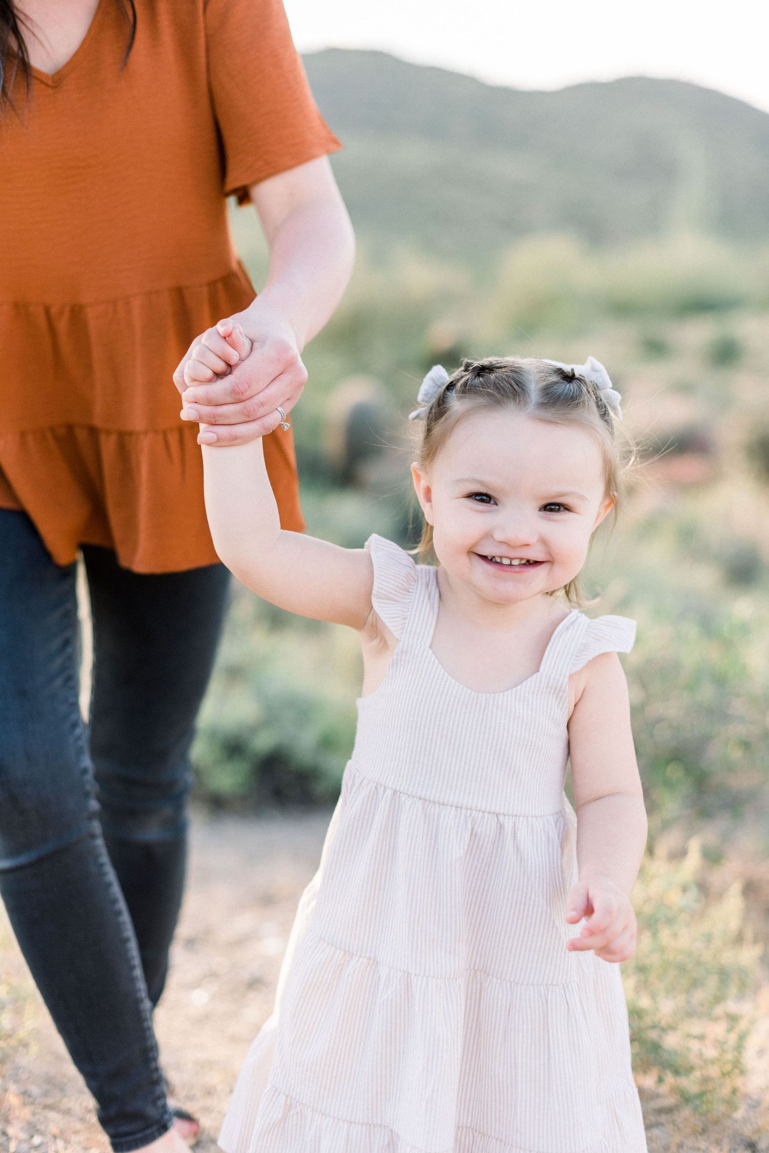 Sweet moment in the desert as child in white dress holds hand while walking.