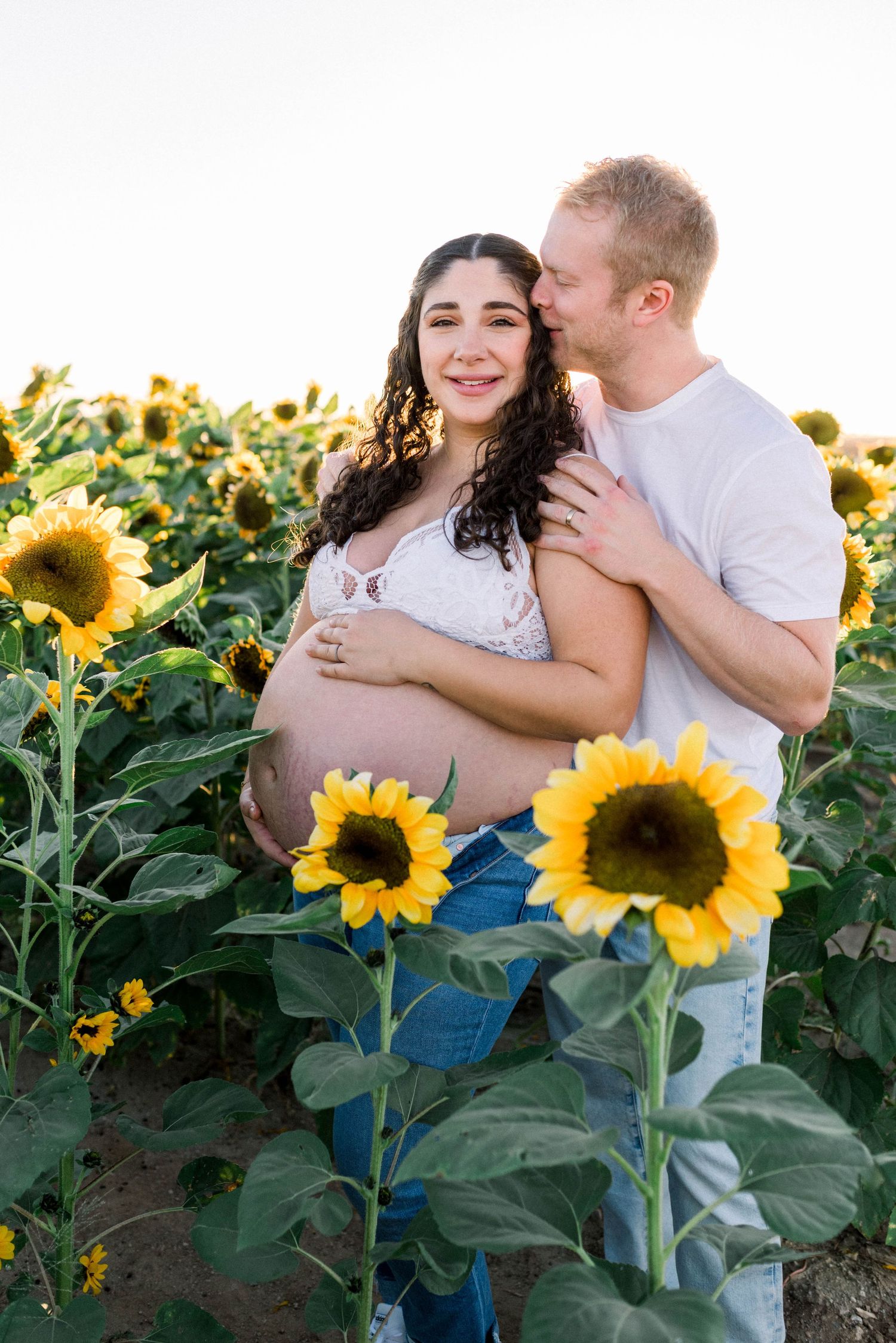 Maternity photo of couple kissing in sunflower field