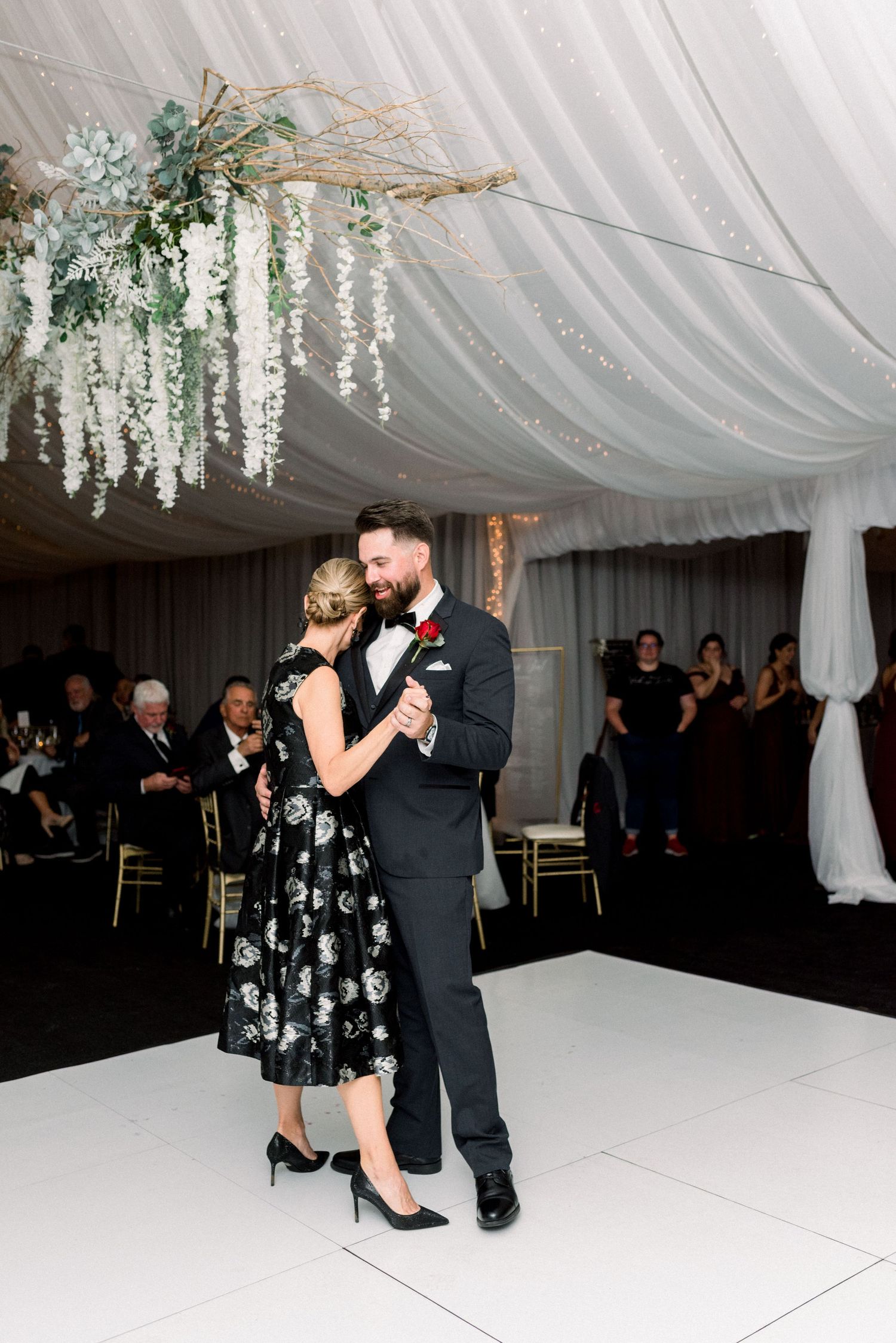 Couple dancing together under elegant floral chandelier at wedding reception.