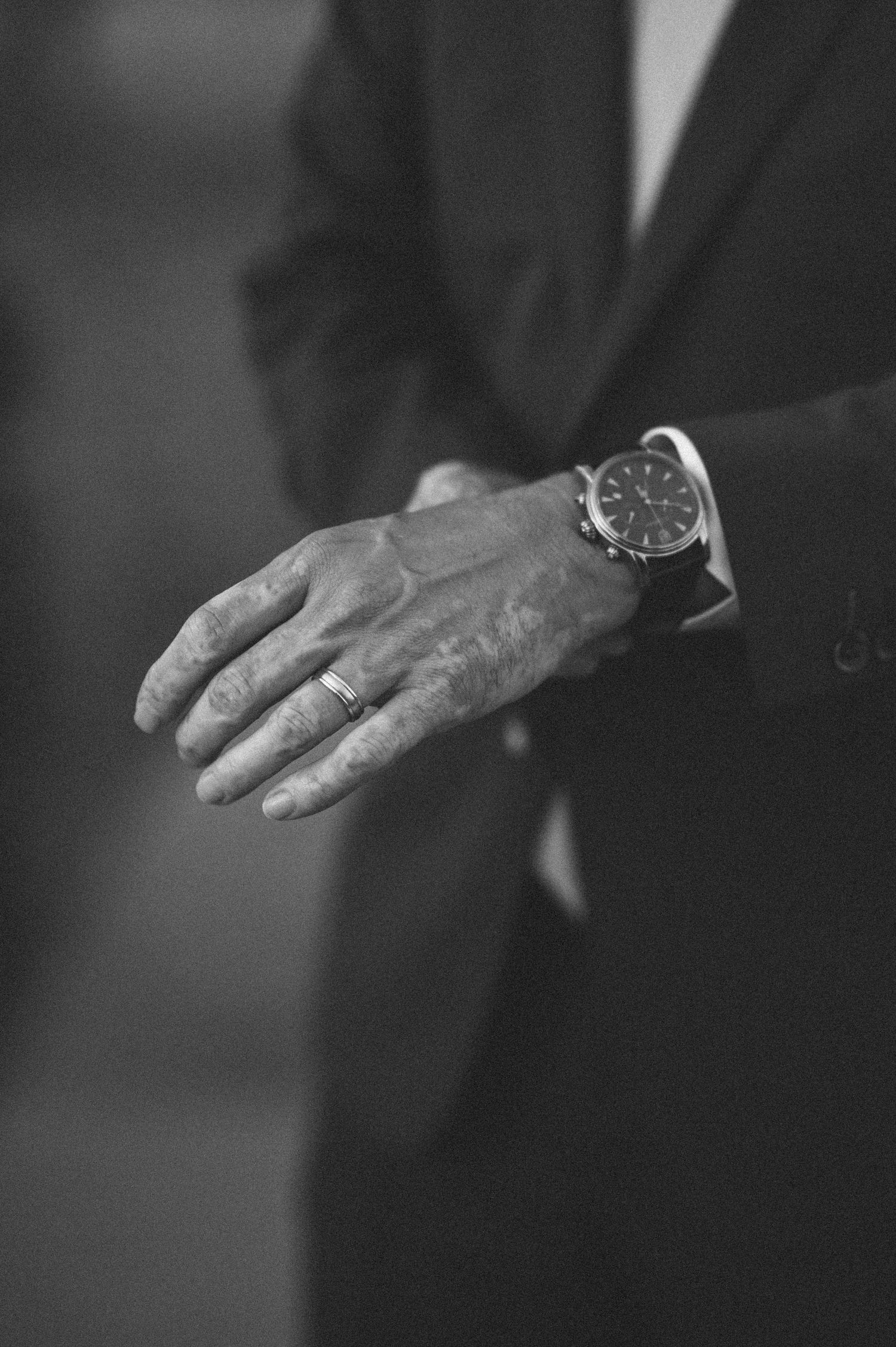 Black and white close-up of hands wearing wedding rings.