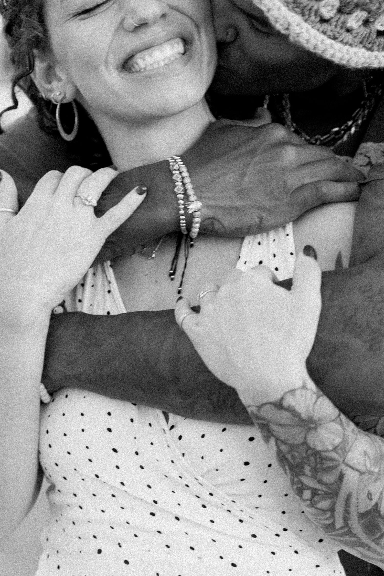 Black and white photo showing a person wearing a polka dot dress and silver jewelry, with a bright smile.