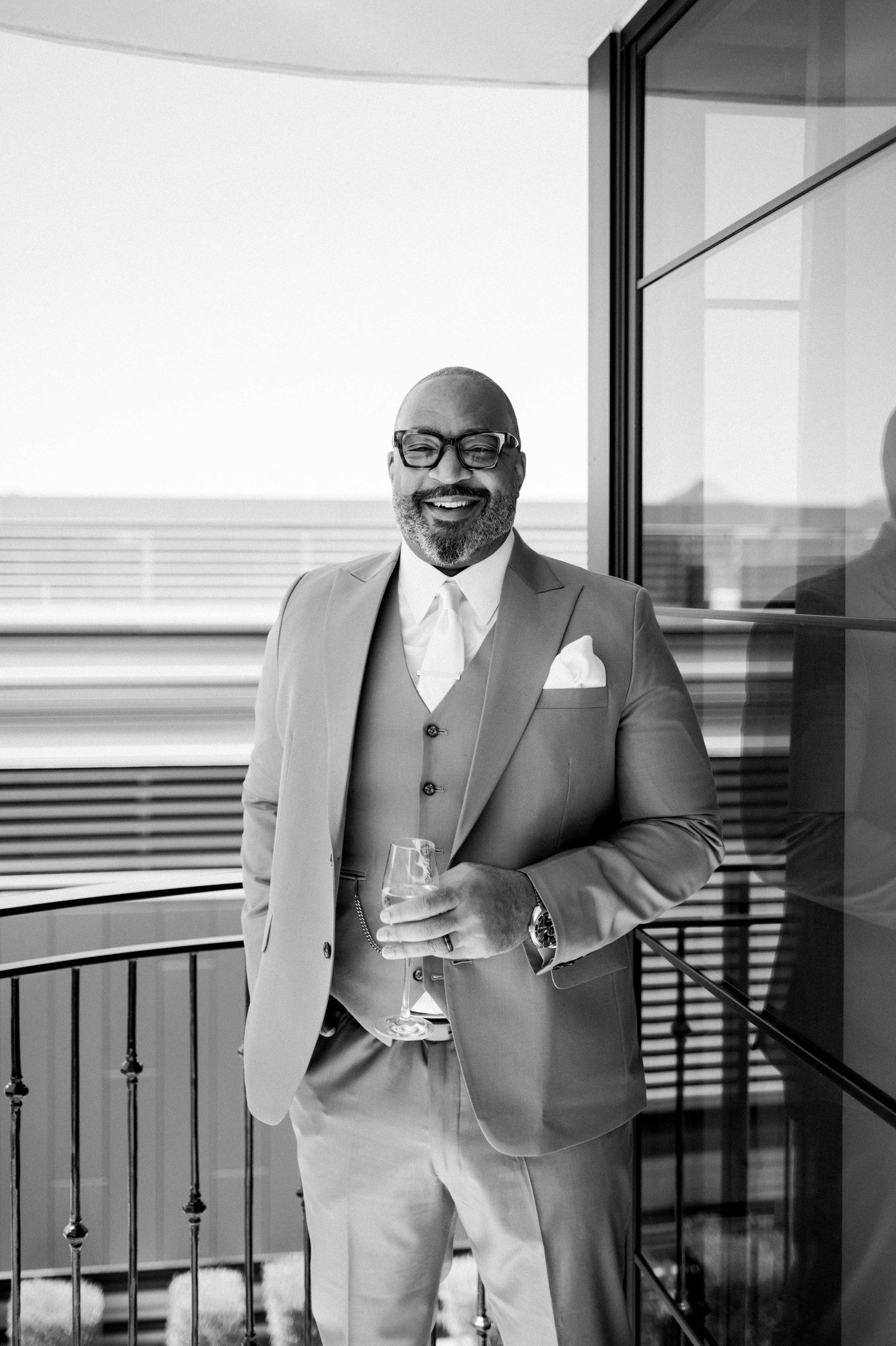 A series of black and white photos showing a person in a stylish three-piece suit holding a coffee cup by a window.