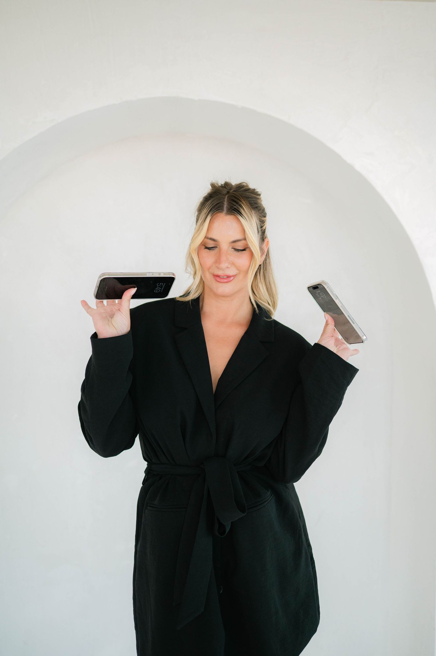 A figure in a black oversized coat strikes playful poses against a white studio background.