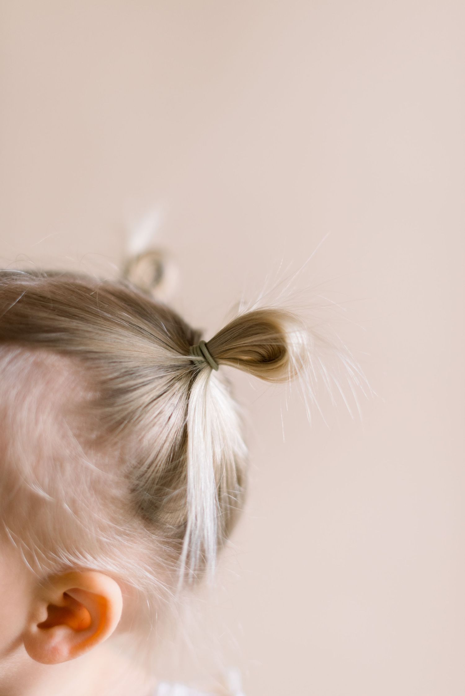 Close-up of a small pigtail hairstyle with wisps of blonde hair.
