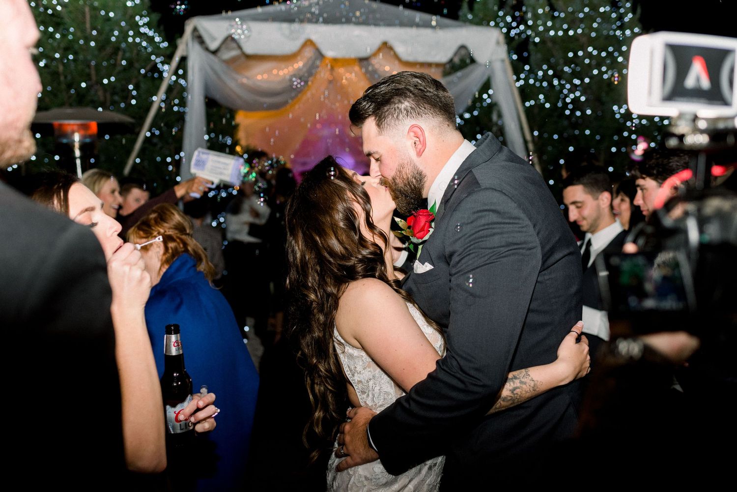 Intimate dance moment under twinkling lights and falling confetti at outdoor wedding reception.