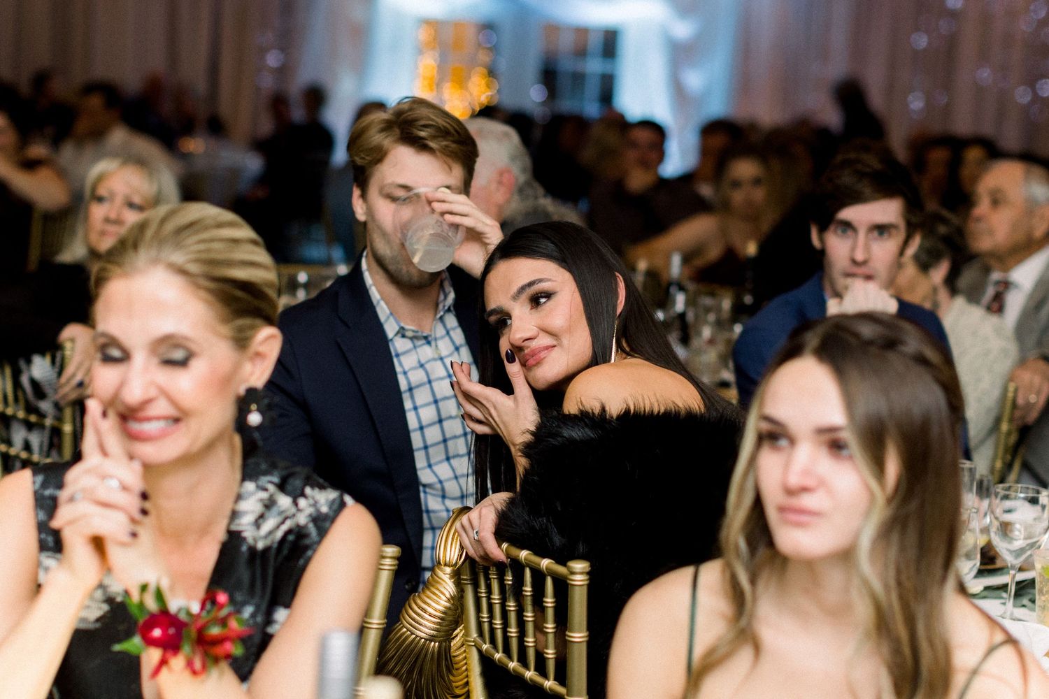 Wedding guests enjoying reception dinner at decorated tables with warm lighting.