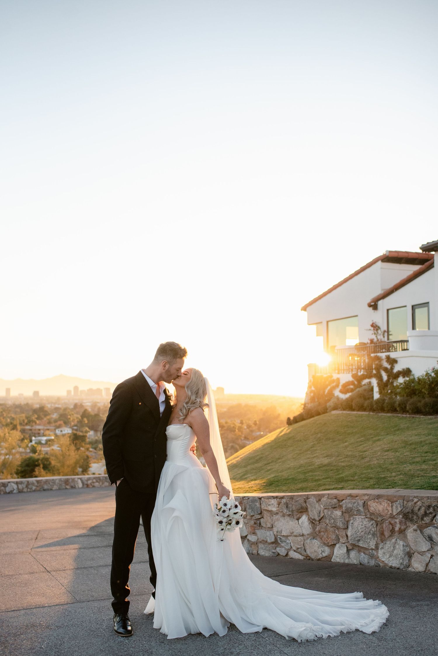 Romantic sunset wedding portrait with couple silhouetted against mountain backdrop.