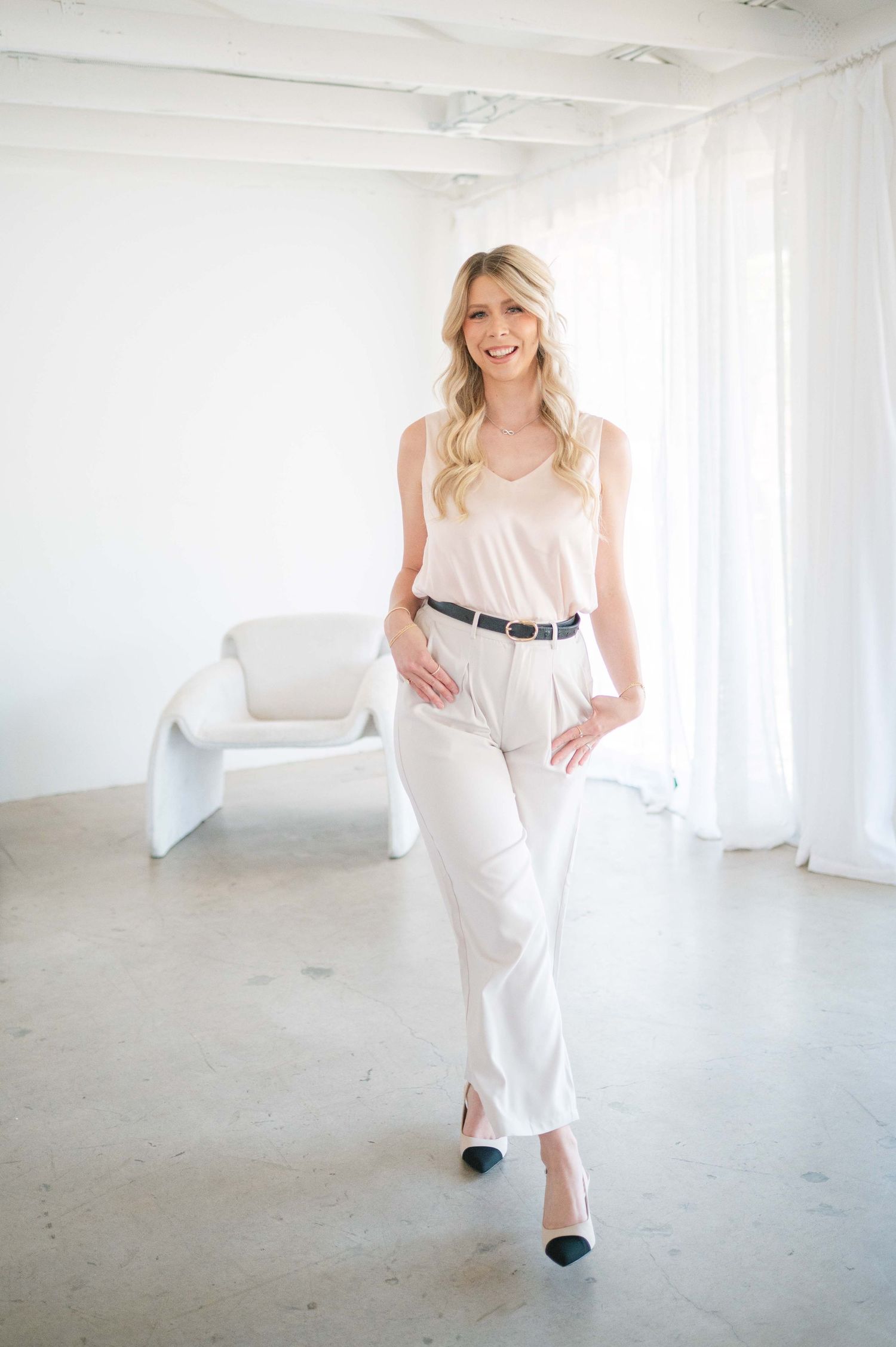 A person in a flowing white dress dances and twirls through a bright minimalist studio space.
