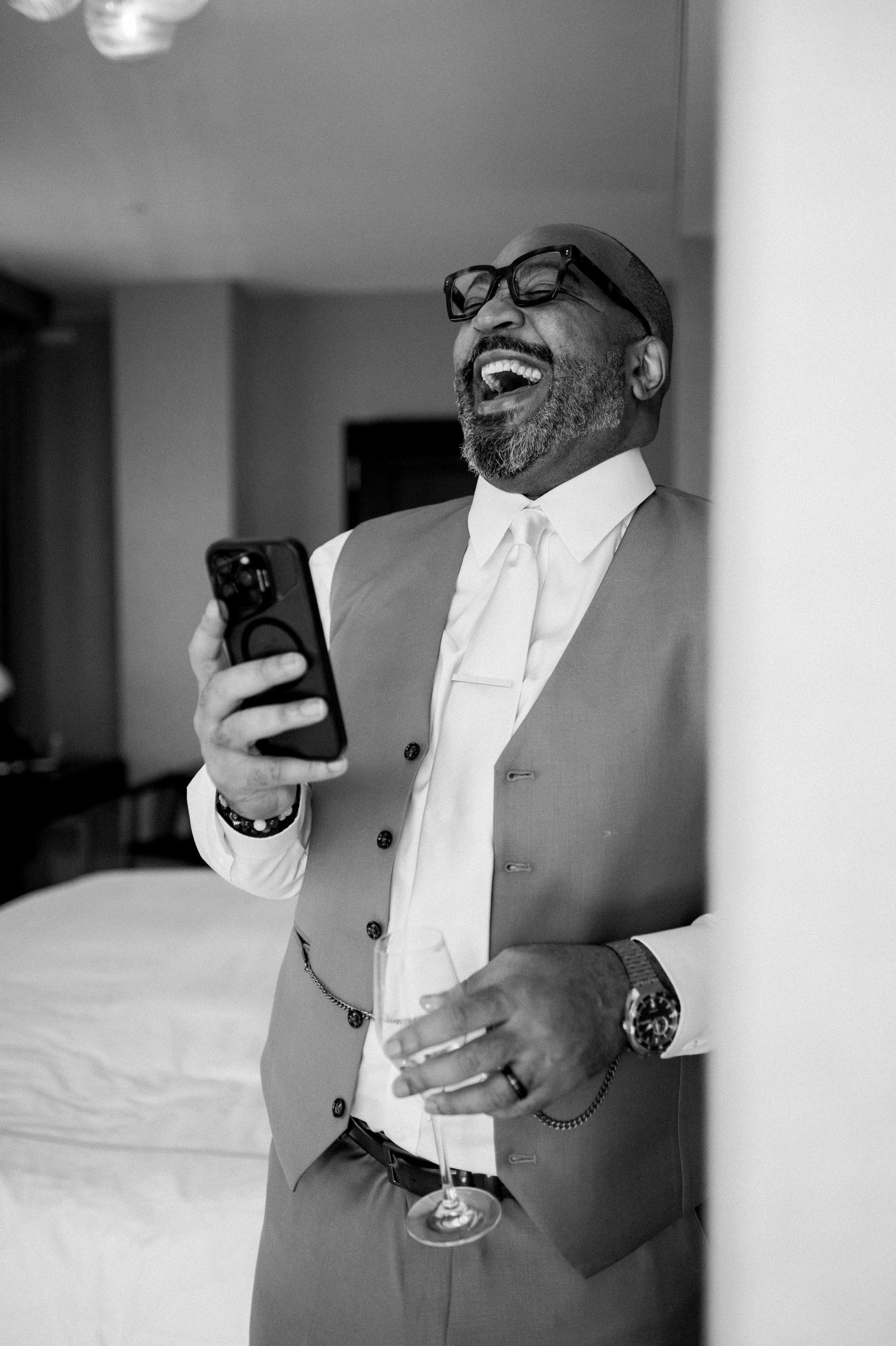 A series of black and white photos showing someone in formal attire checking their phone while holding a drink.