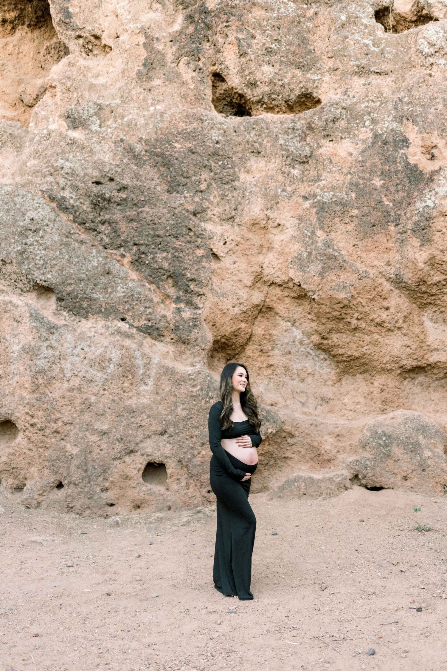 Maternity silhouette against dramatic desert rock wall backdrop.