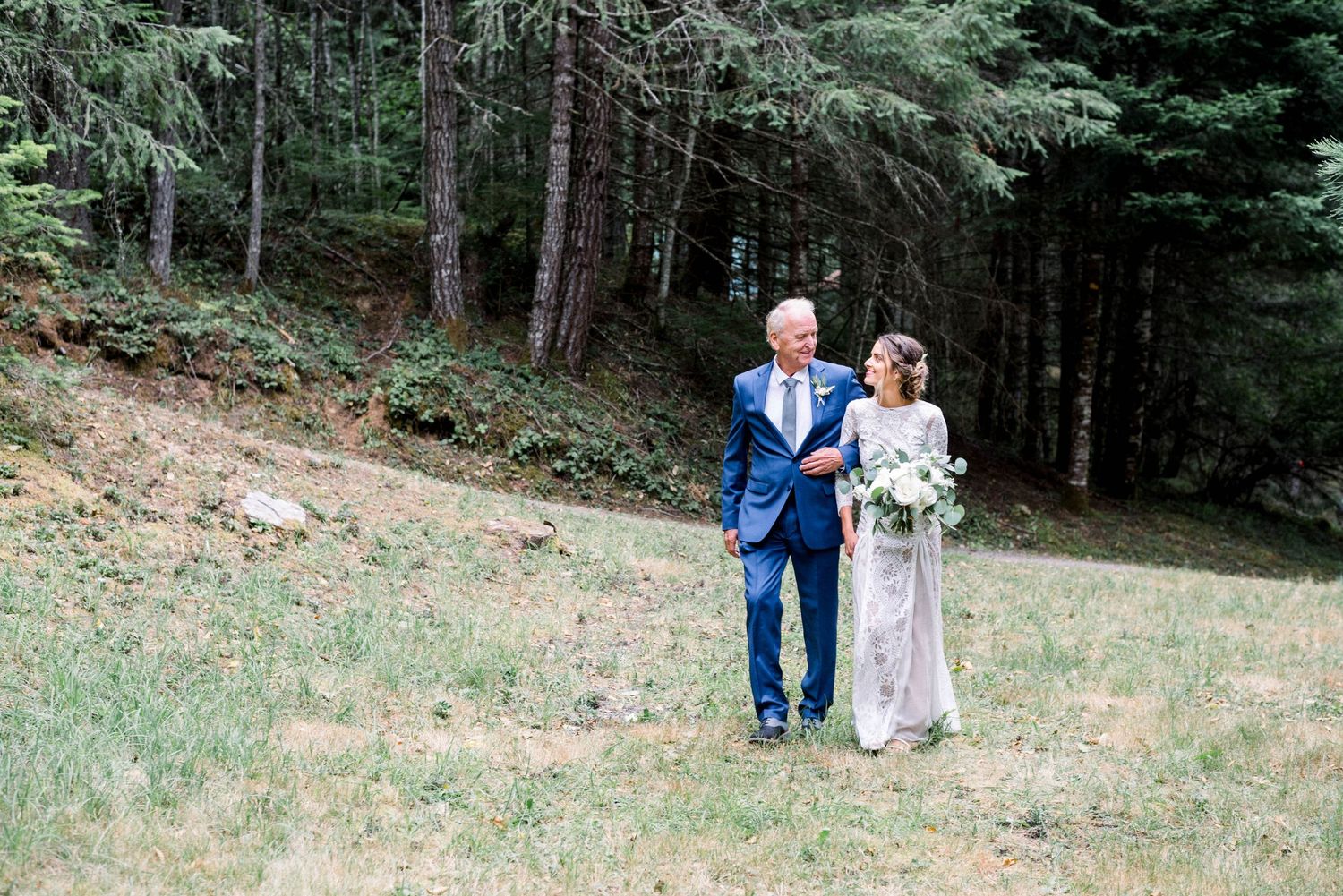 A couple walks down a forest path during their intimate outdoor wedding.