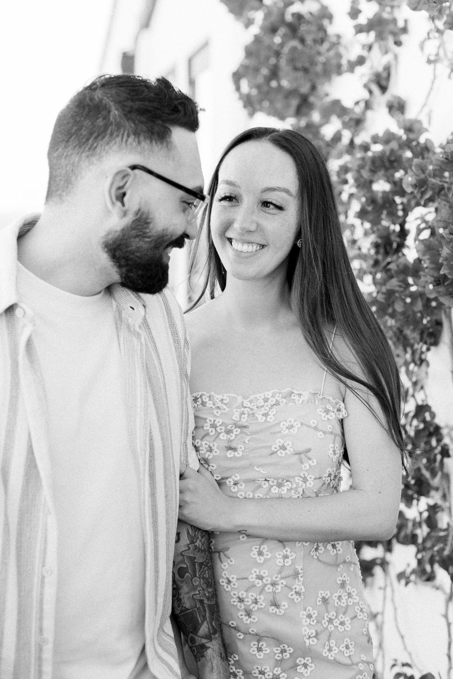 Black and white portrait of a couple sharing a joyful moment outdoors.