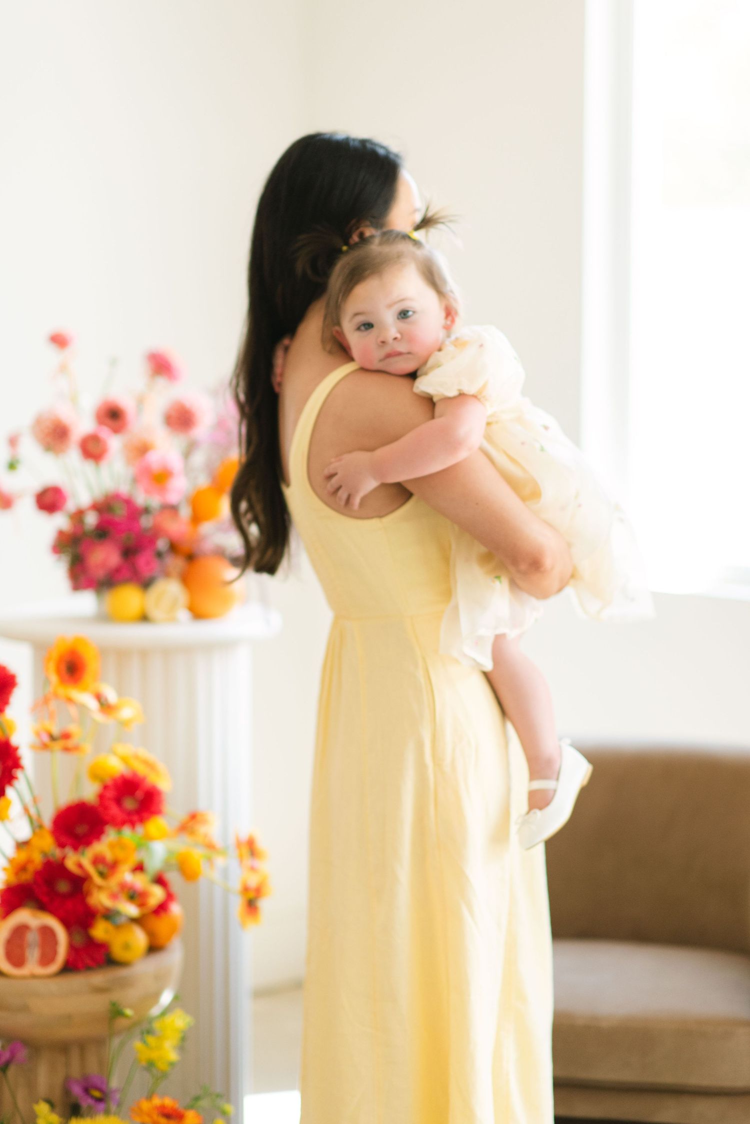 A sunny indoor portrait with vibrant florals and citrus decor in the background.