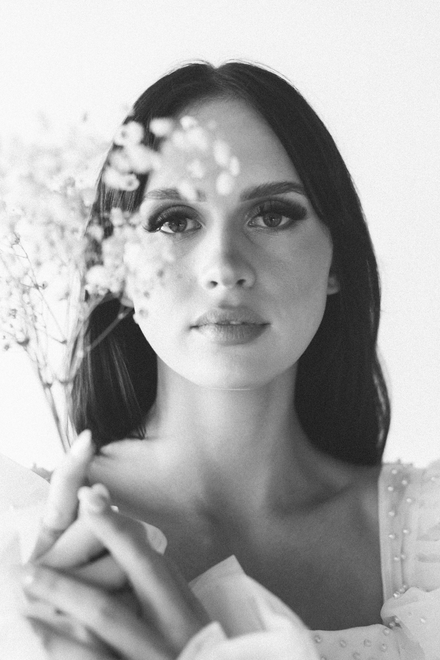 Soft black and white portrait with delicate floral elements and classic beauty styling.