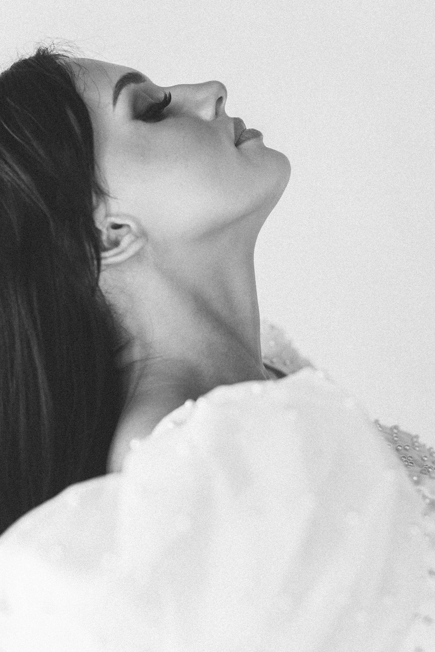 Artistic black and white profile portrait showing delicate details of white lace garment.