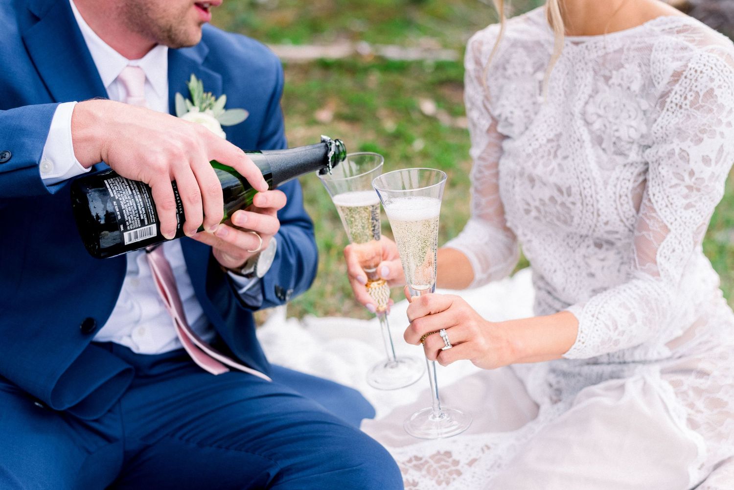 Closeup of hands pouring champagne during outdoor forest celebration.