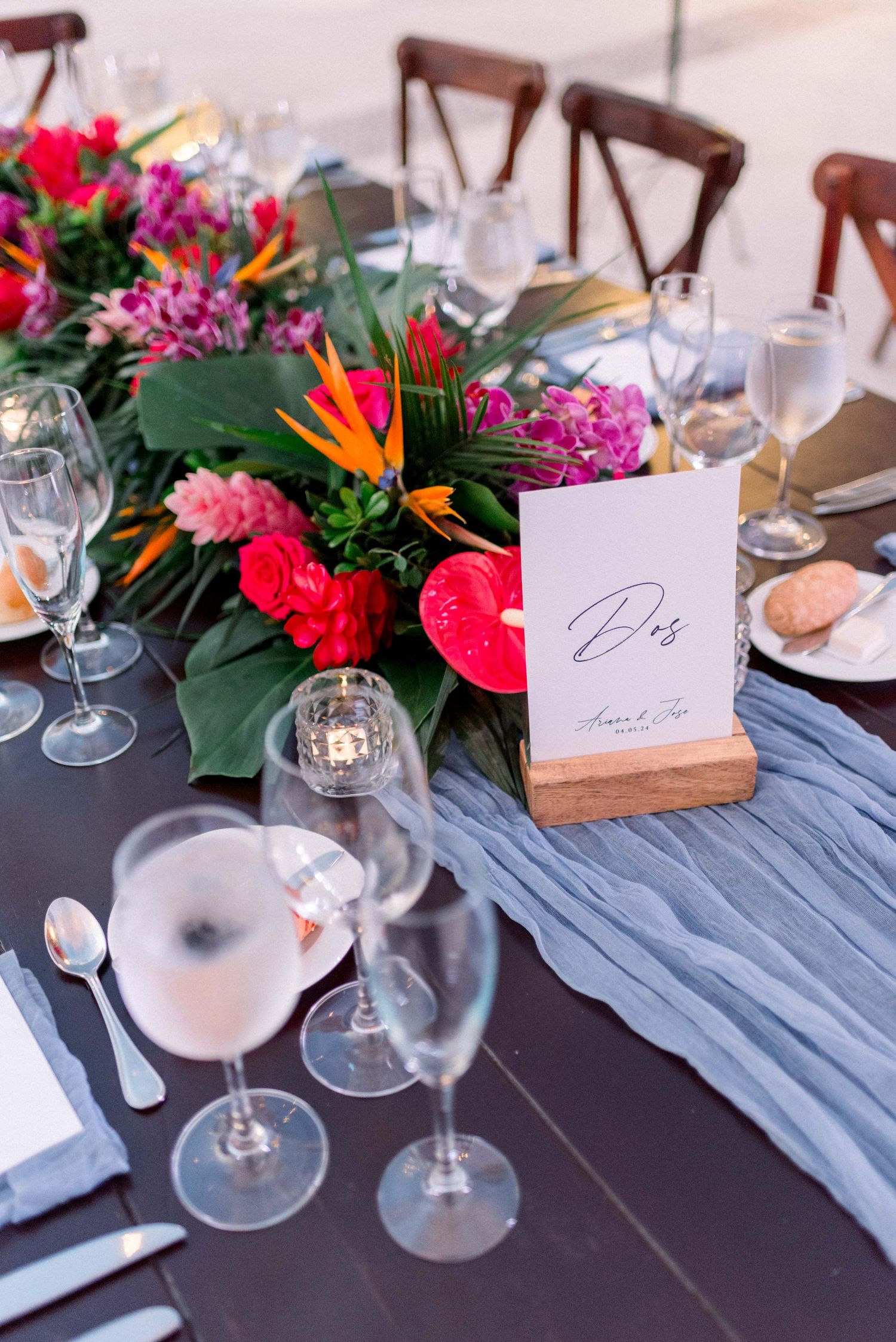 Vibrant tropical floral centerpiece with birds of paradise and pink flowers on elegant table setting.
